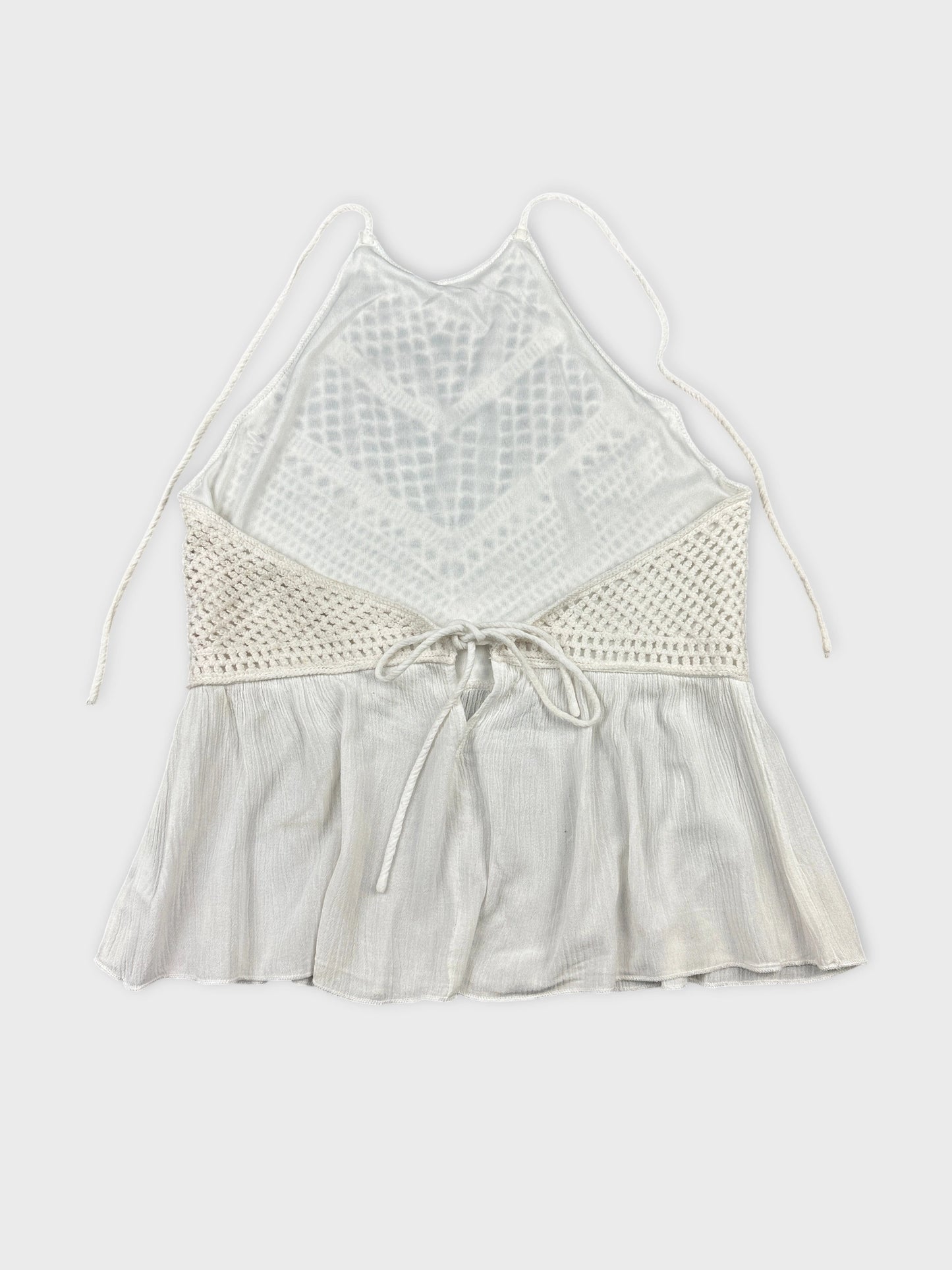 Back view of a white women’s halter top with crochet detailing.