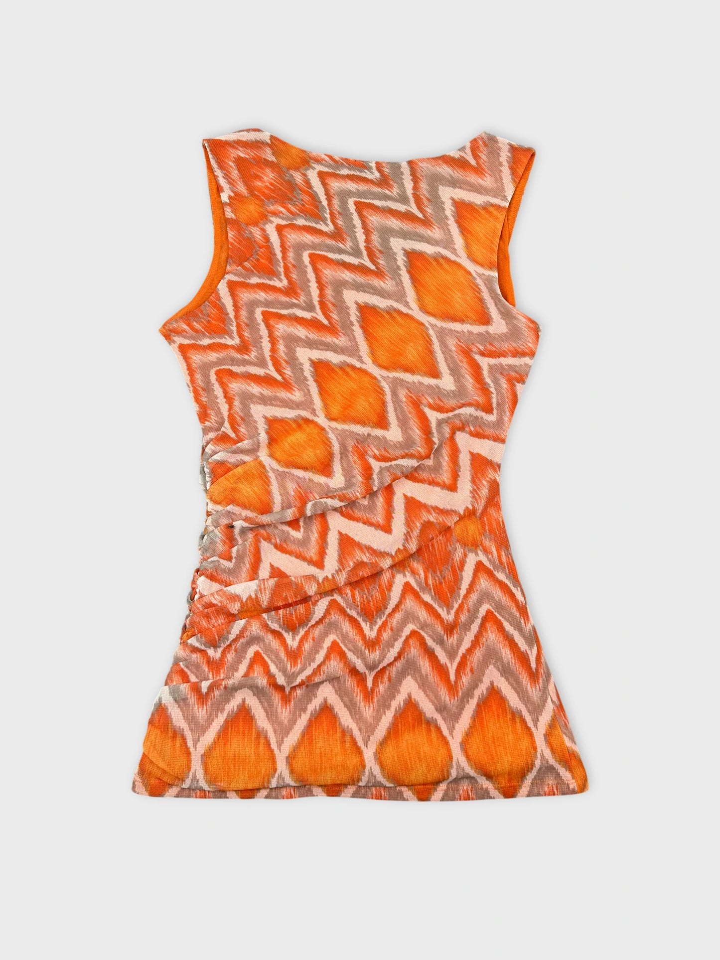 Back view of a sleeveless orange zigzag patterned top.