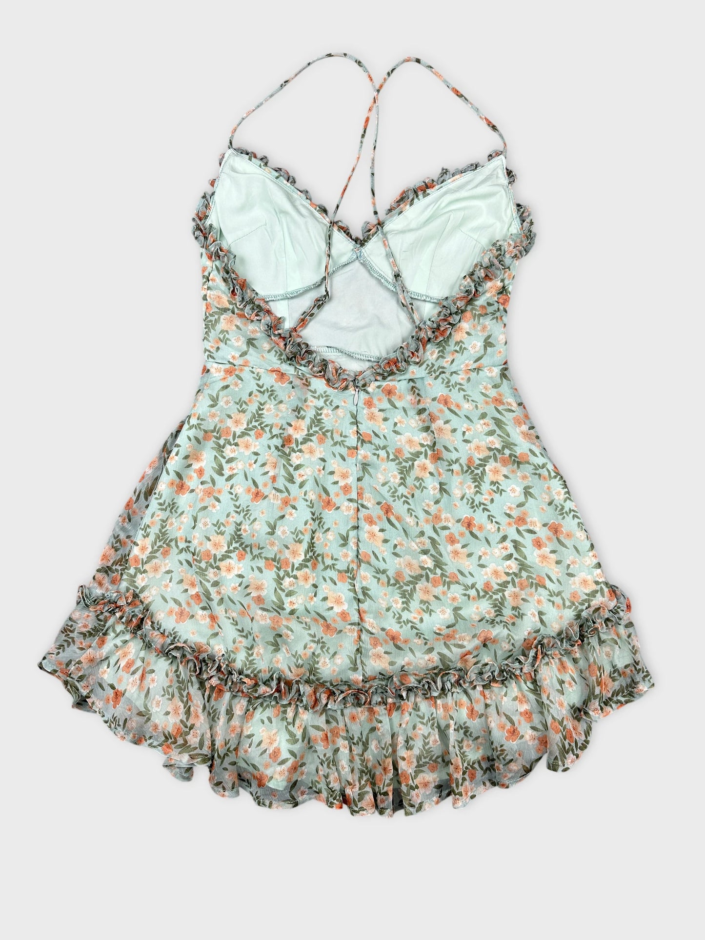 Back view of a floral print women’s top in light blue with ruffled trim.