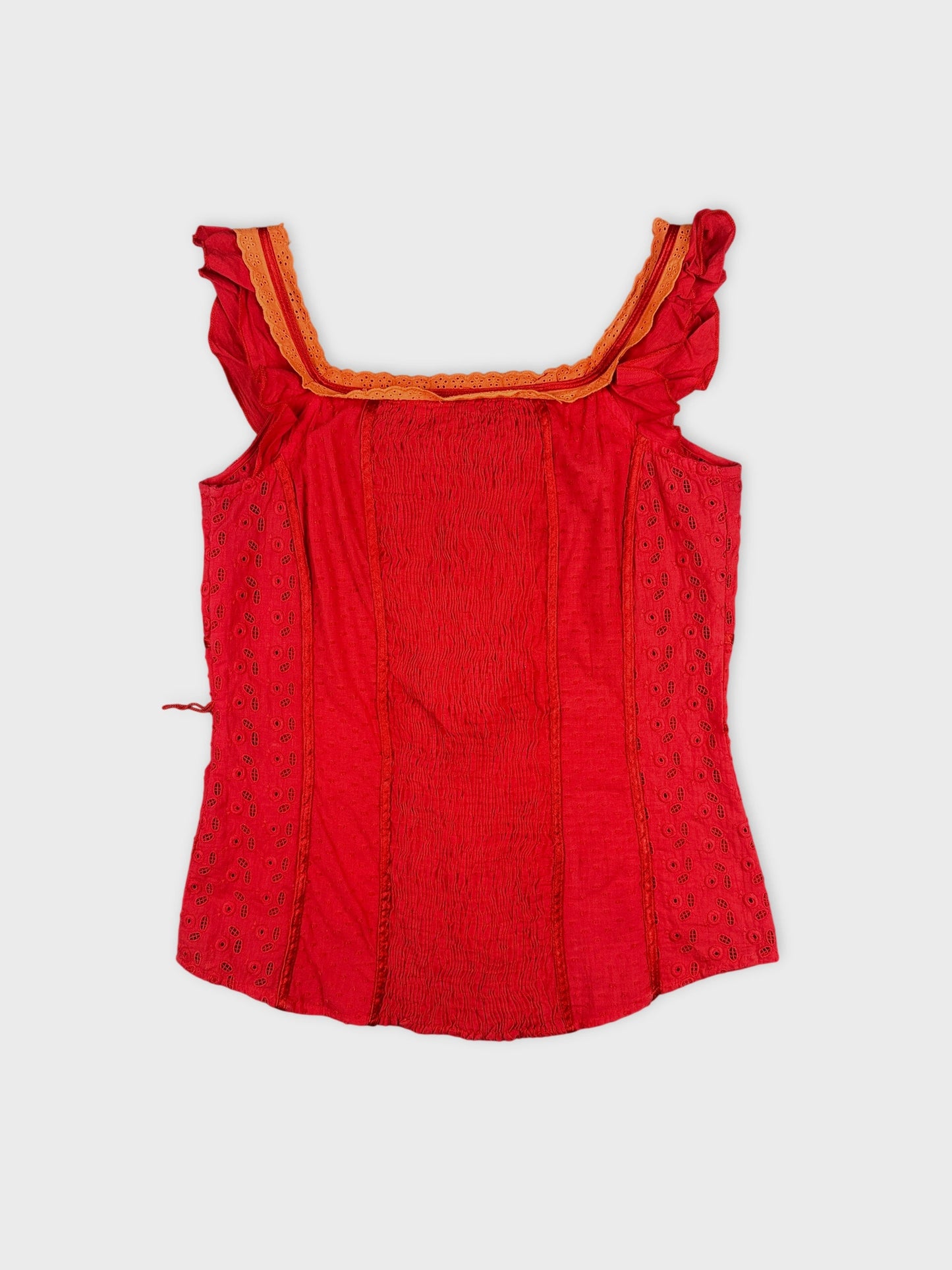 Back view of a red upper body top with decorative trim and textured panels.