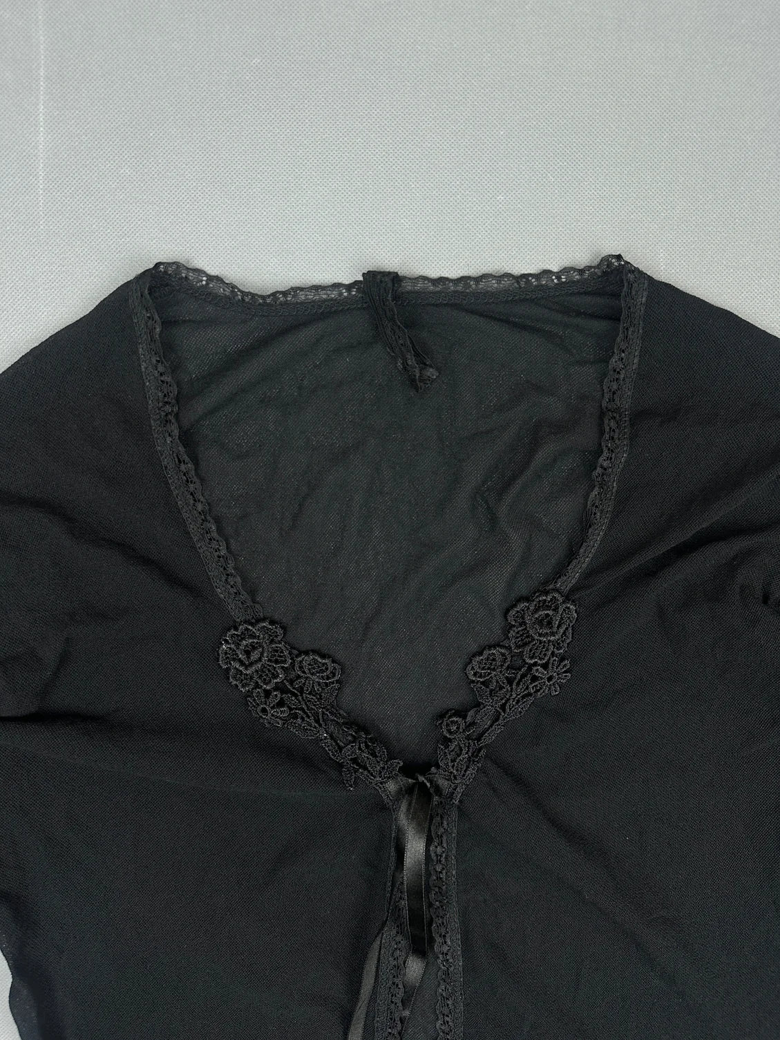 detail view of a black women's top featuring floral lace trim.