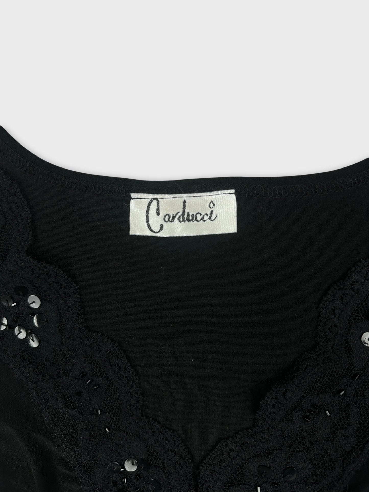Detail view of a black women's top featuring lace trim and sequins.