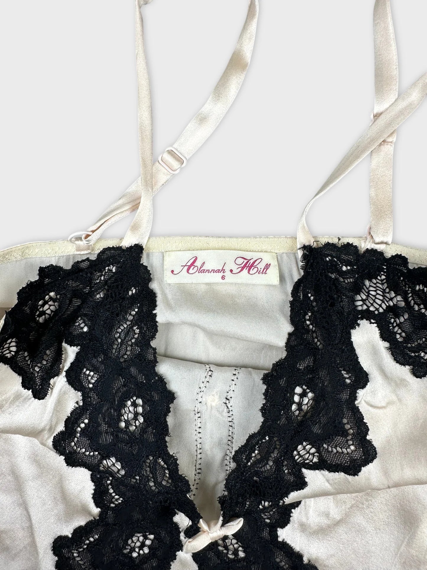 Detail view of a cream colored top with black lace trim