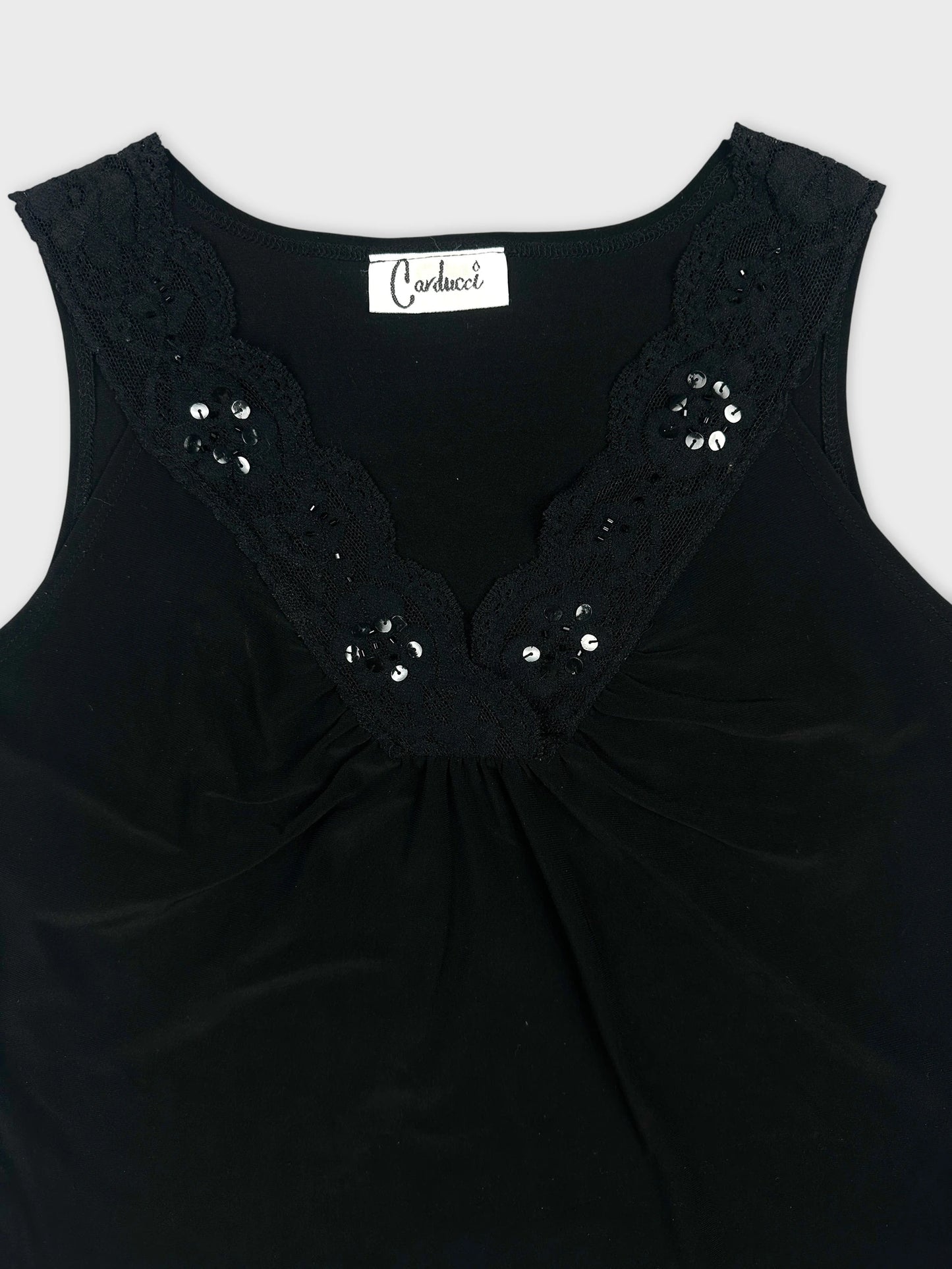 Detail view of a black sleeveless top with lace trim and sequin embellishments.