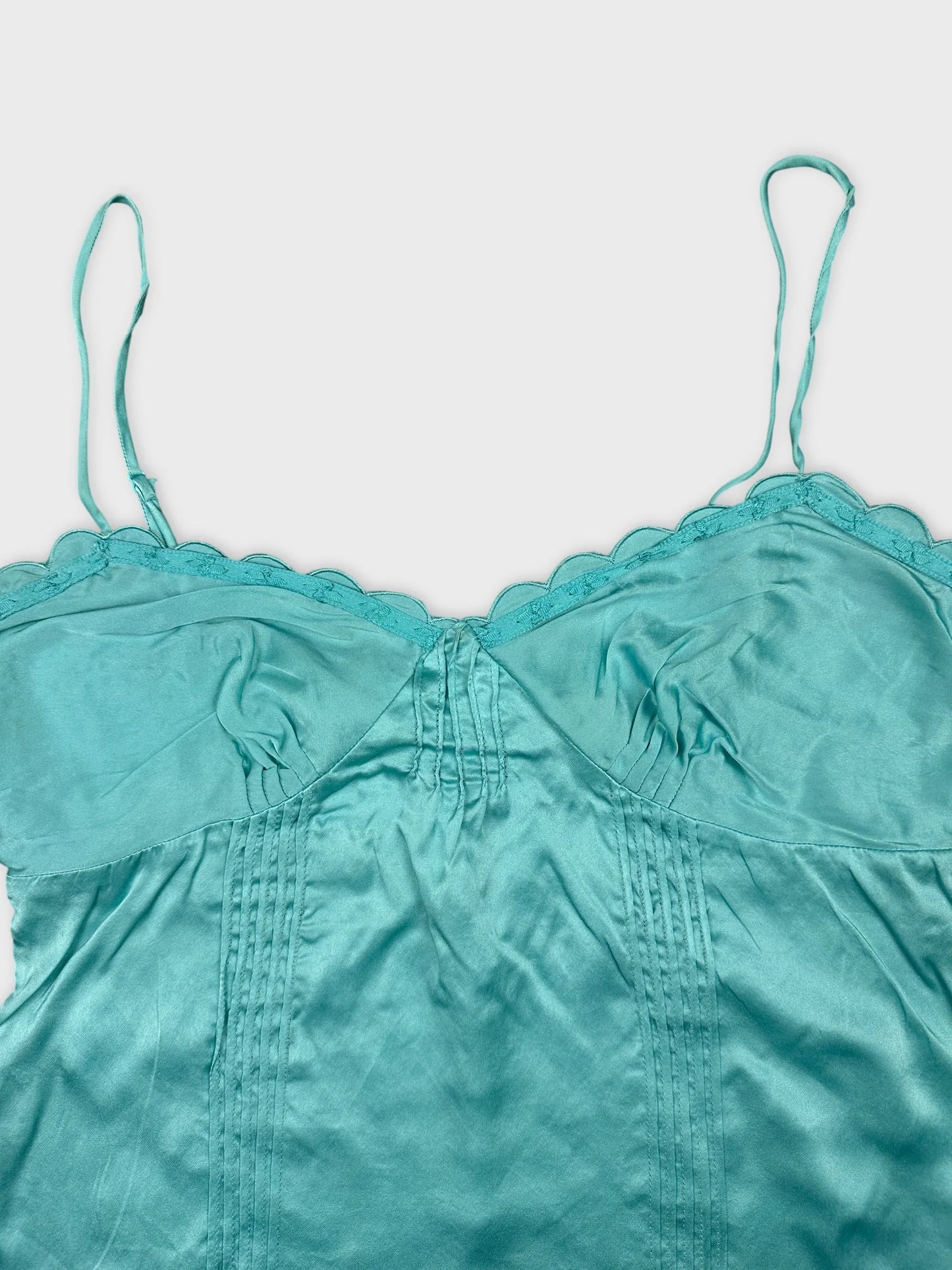 Detail view of a turquoise women's top with scalloped trim.