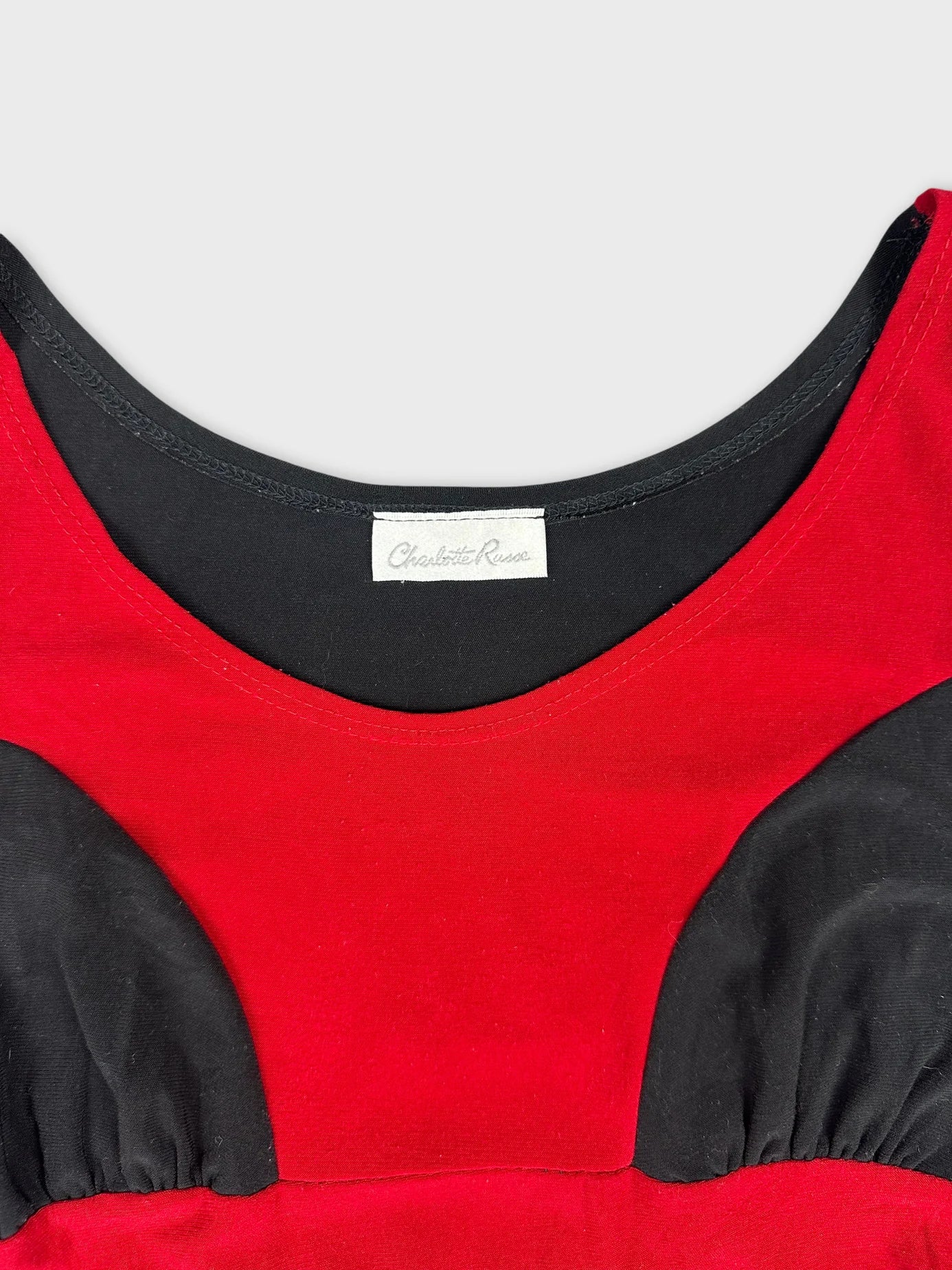 detail view of a red and black top featuring a scoop neckline.
