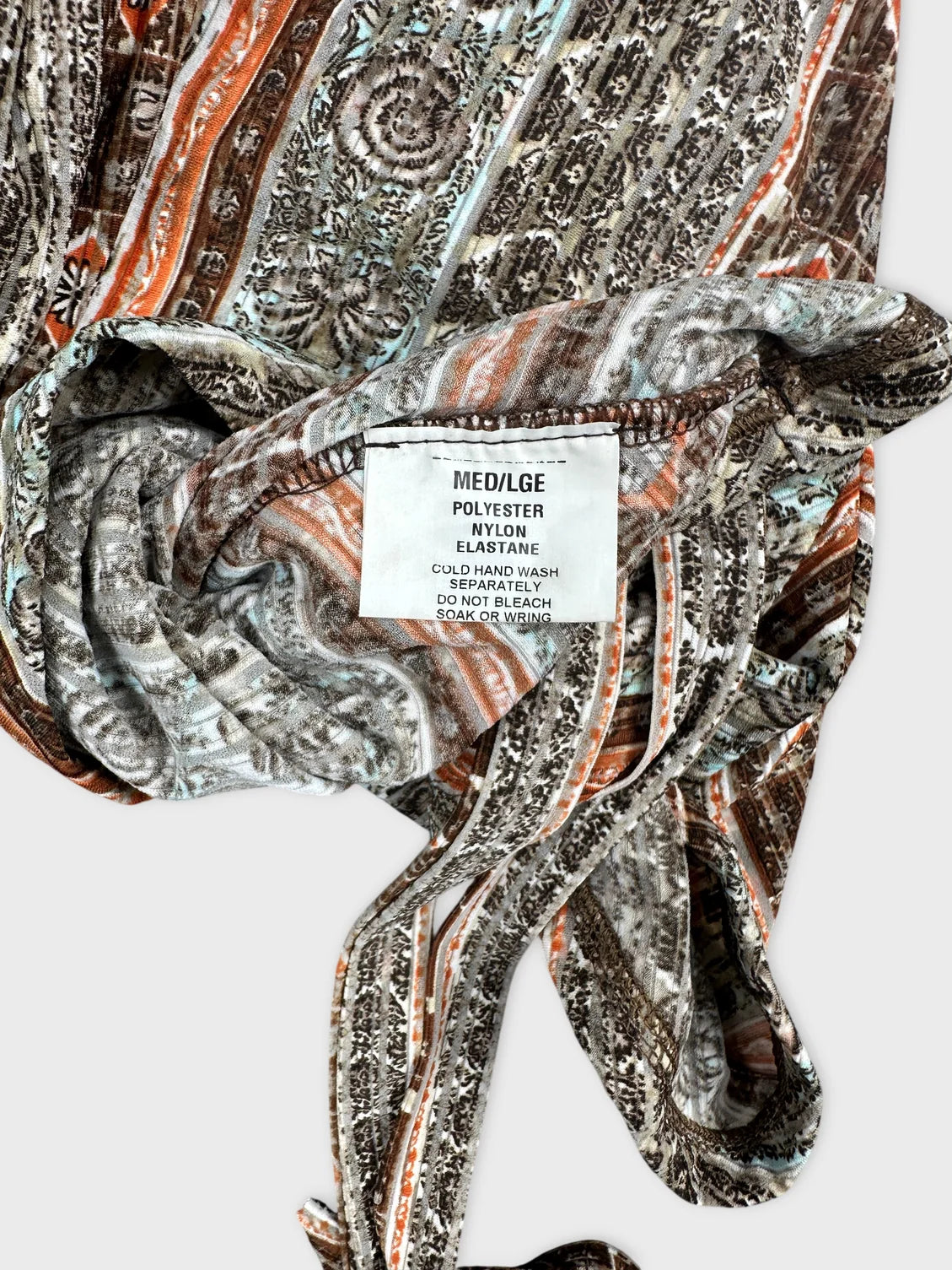 Detail view of a vintage women’s top featuring multicolored paisley patterns.