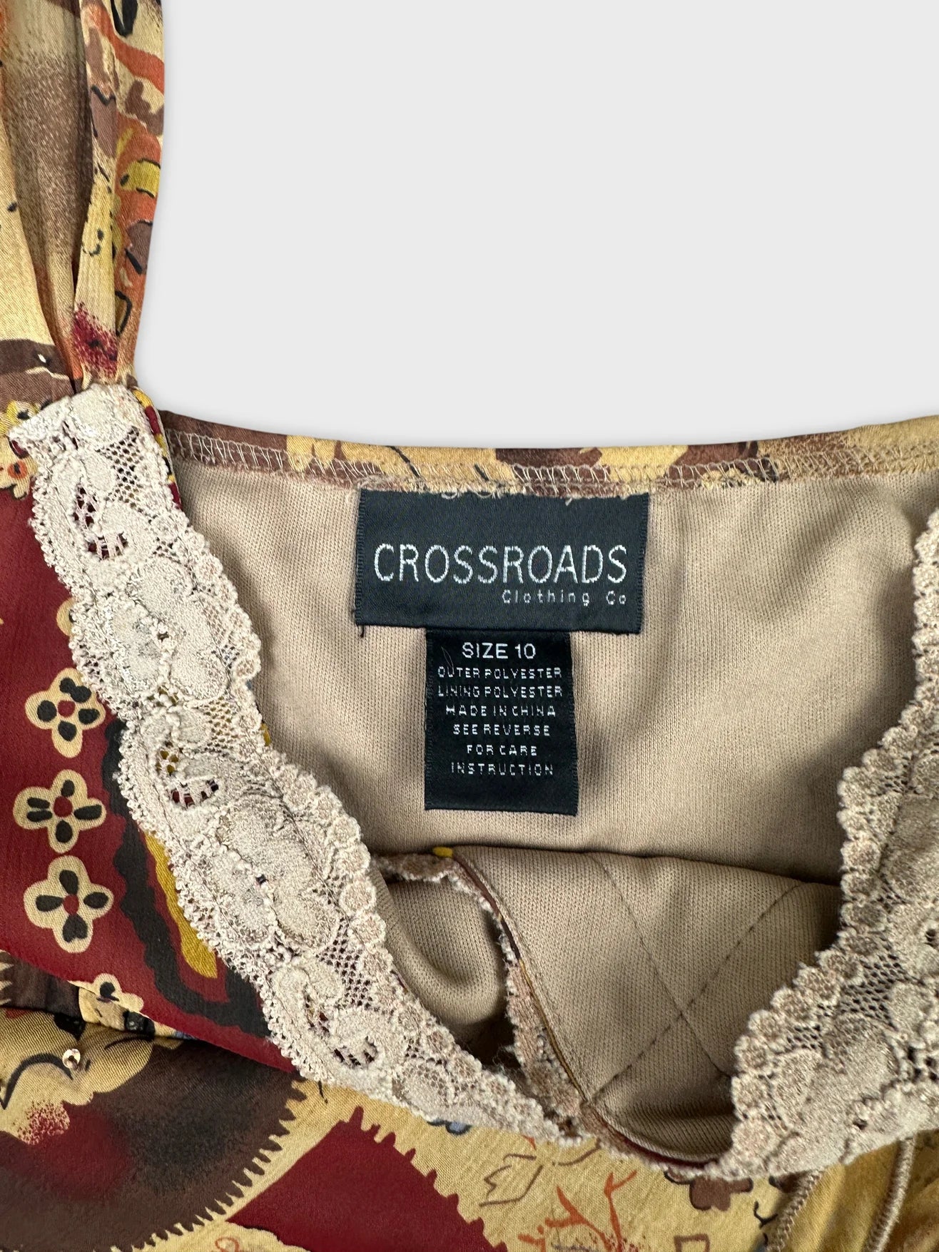 Detail view of a vintage floral top with lace trim in warm tones.