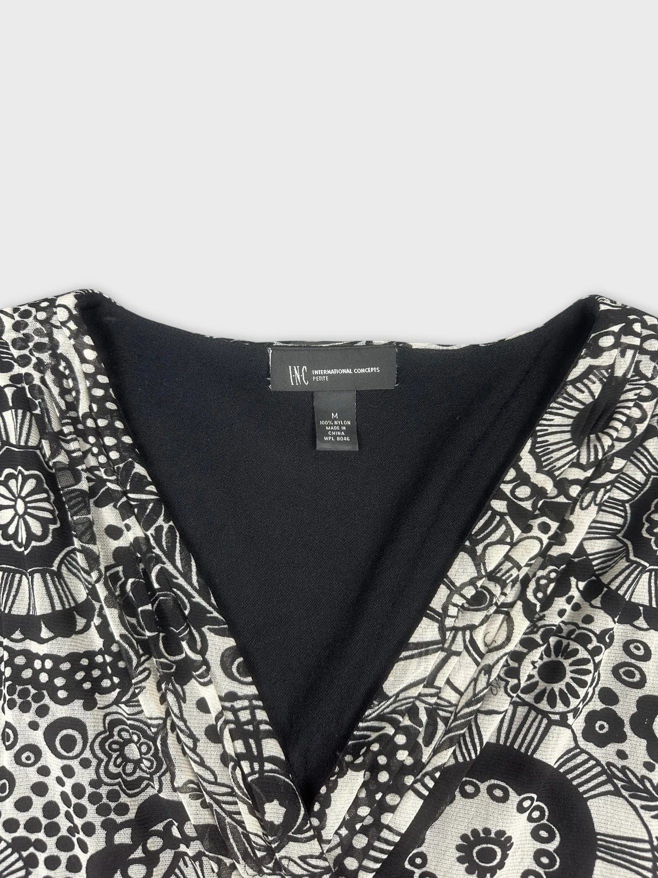 Detail view of a vintage black and white patterned top with a deep V-neck.