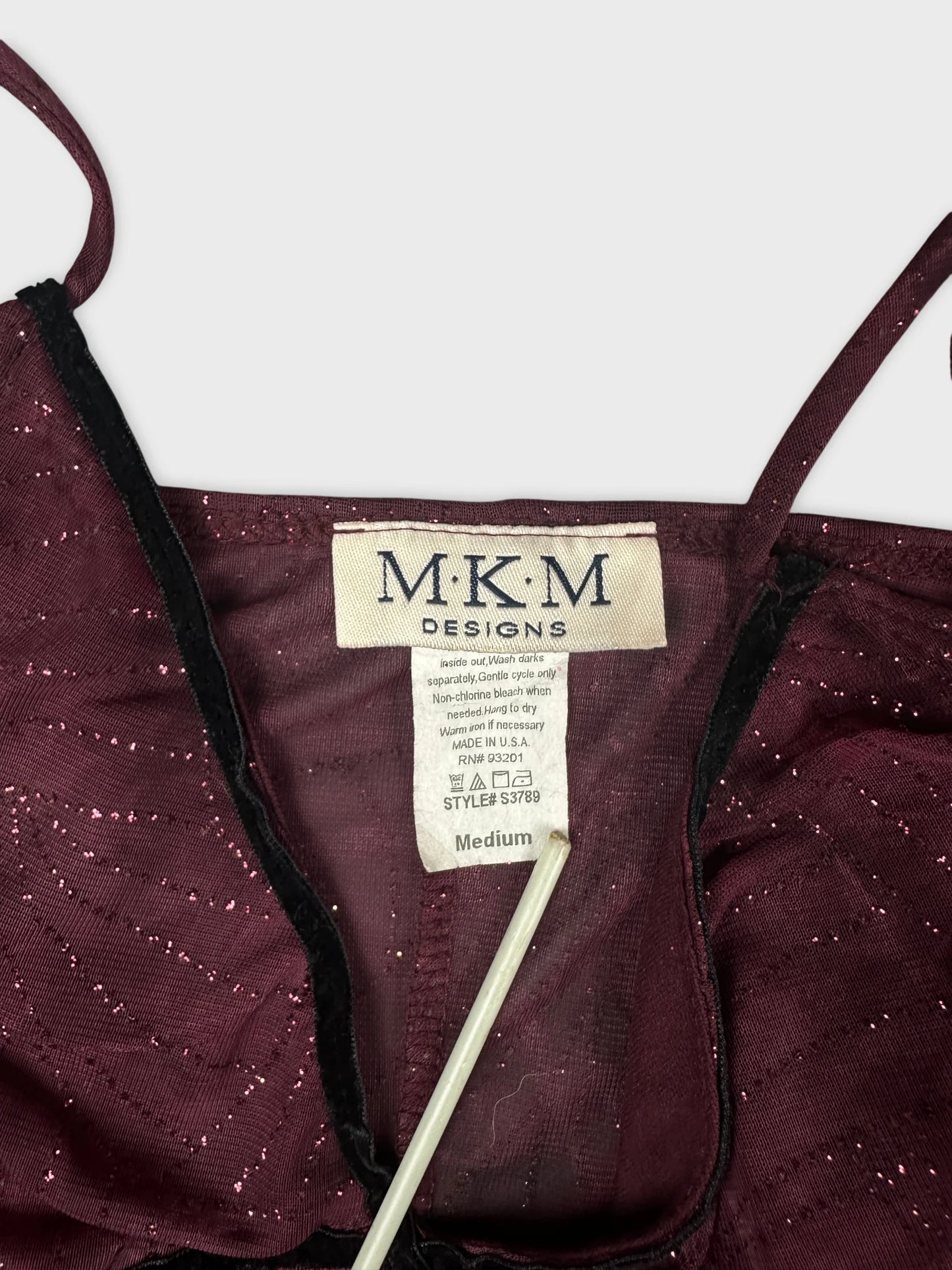 Detail view of a burgundy top featuring a sparkly pattern and adjustable straps.