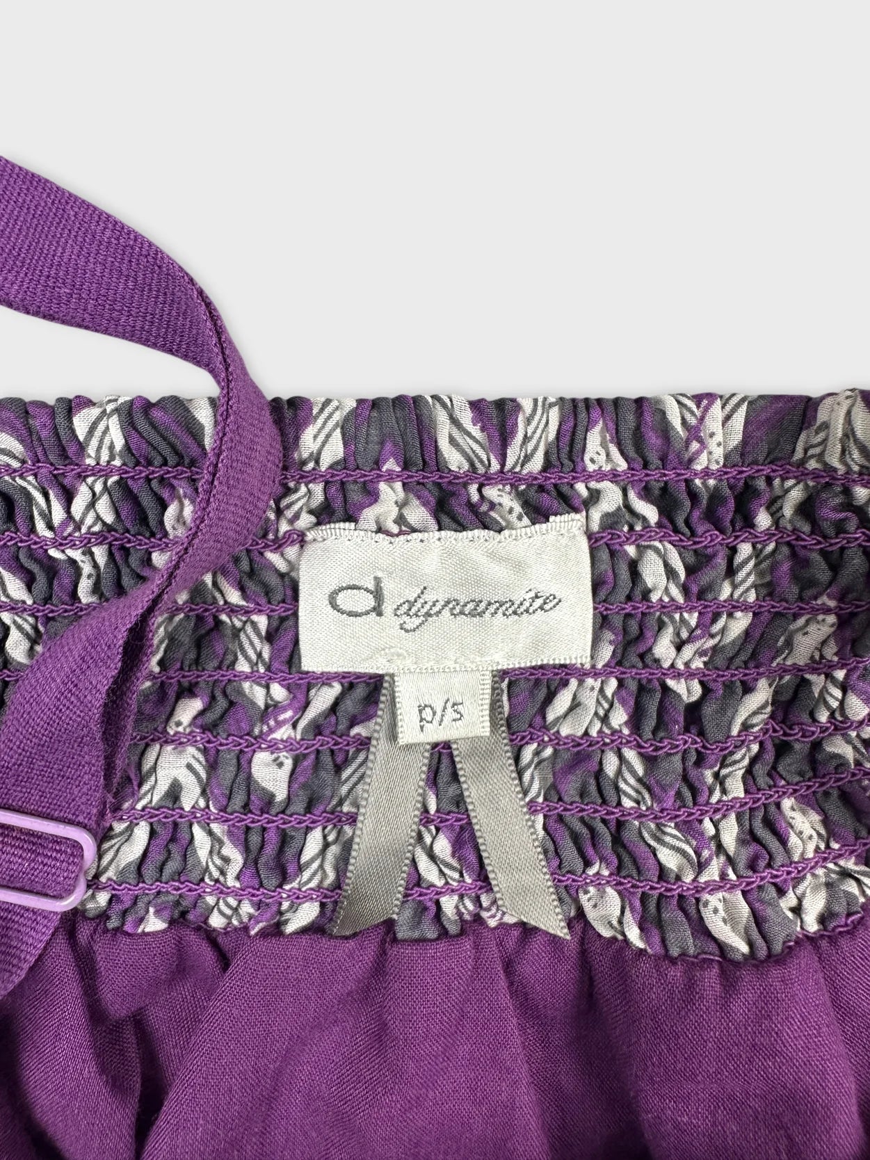 Detail view of a purple vintage top showcasing smocked design and adjustable straps.