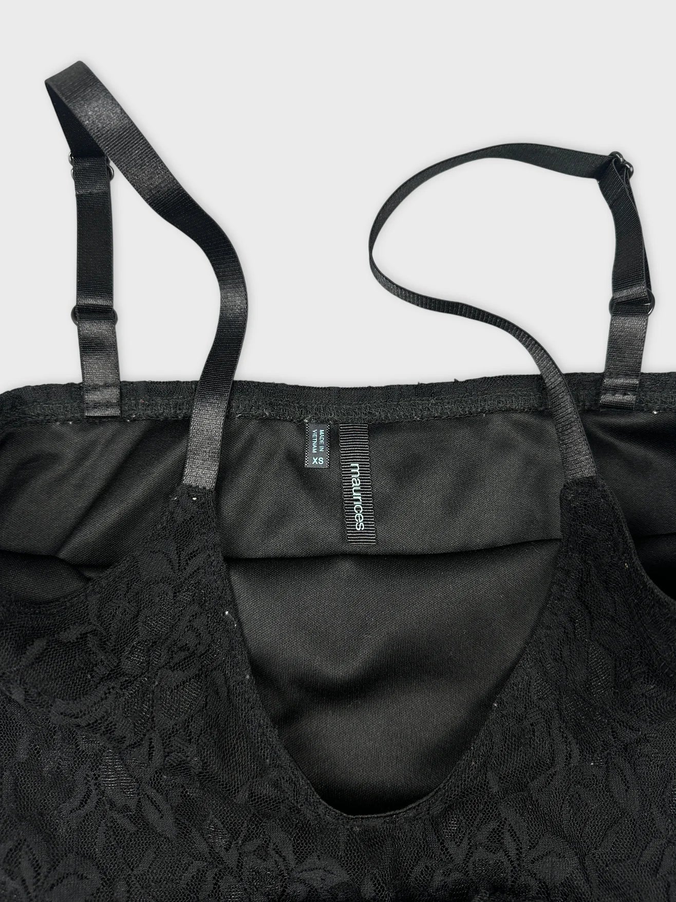 Detail view of a black lace trim camisole with adjustable straps.