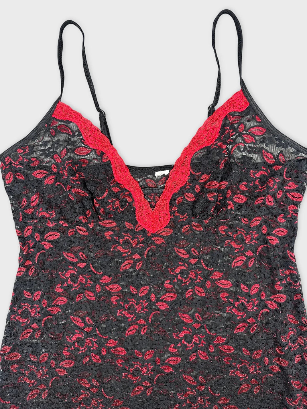 Detail view of a black lace top with red trim and floral pattern