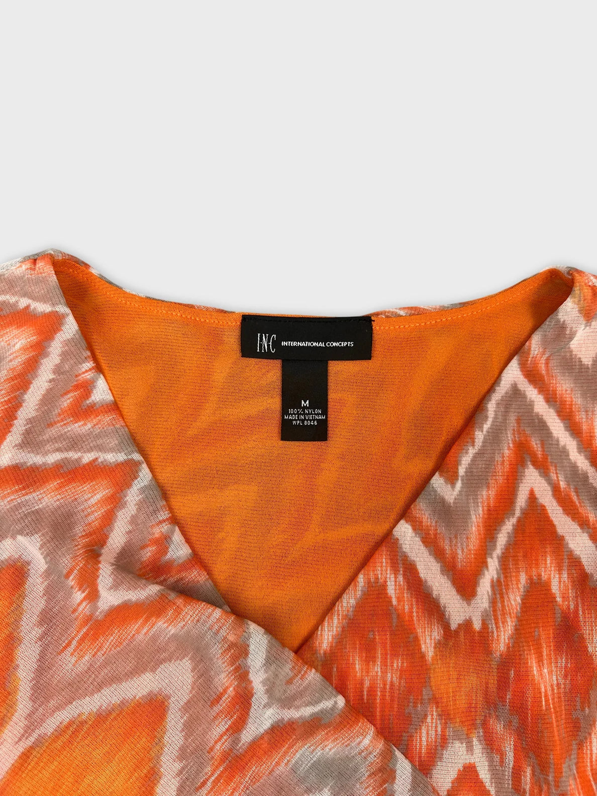 Detail view of a vintage top in orange with zigzag pattern.