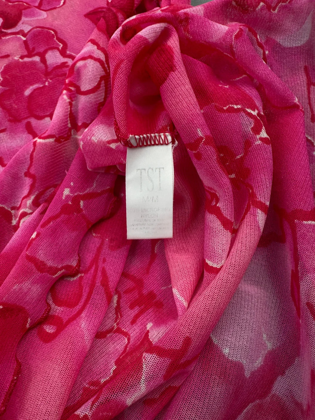 Detail view of a pink floral vintage women’s top with a label.