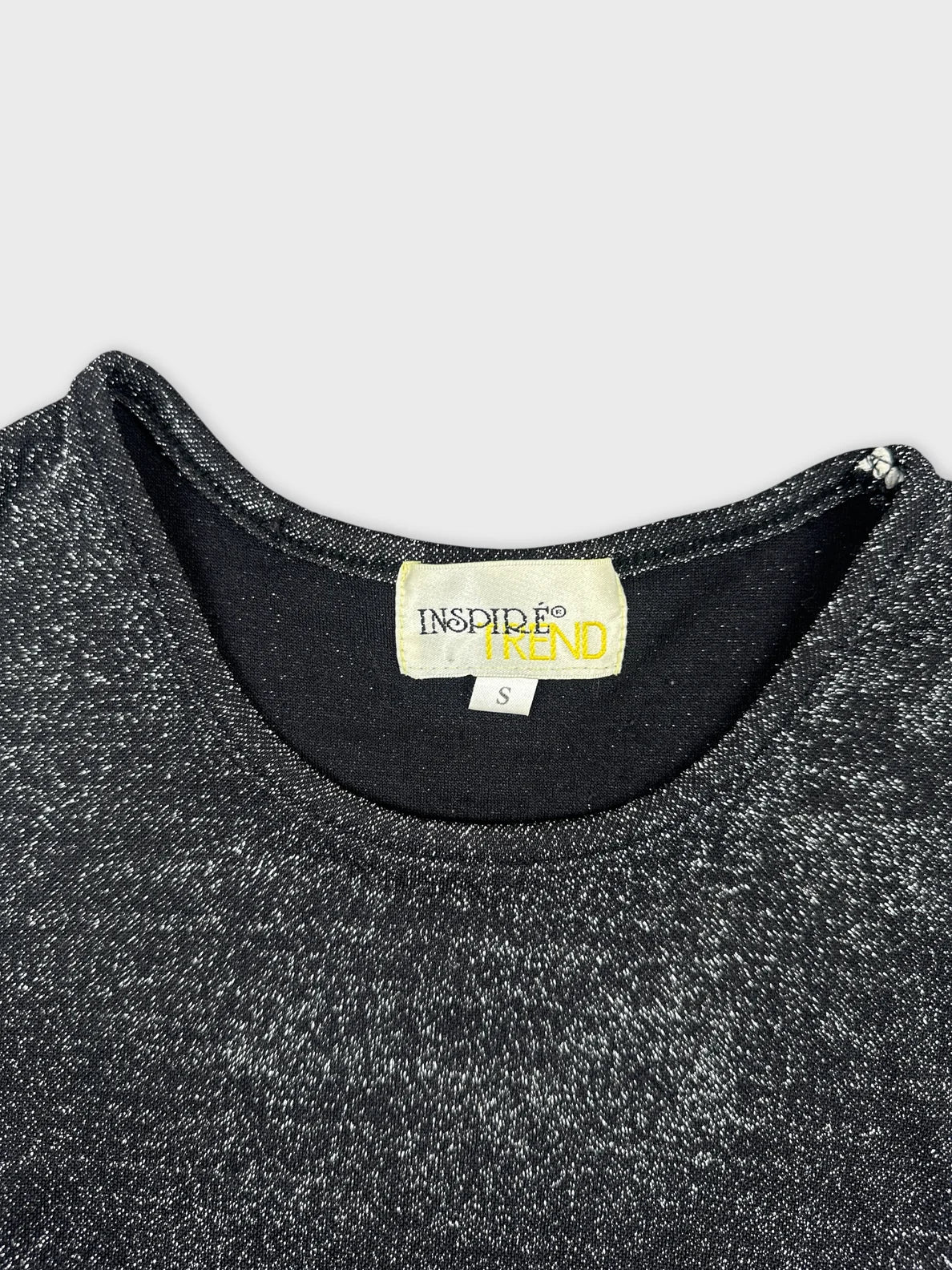 Detail view of a black women’s top with a round neckline.