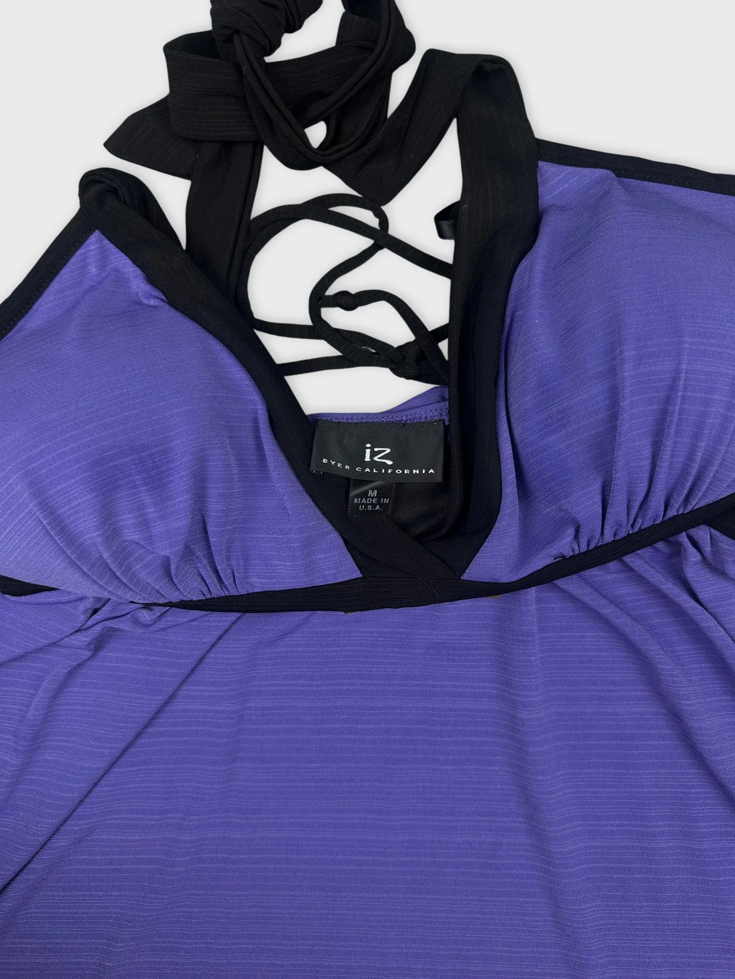 Detail view of a purple halter top with black trim and crisscross straps.
