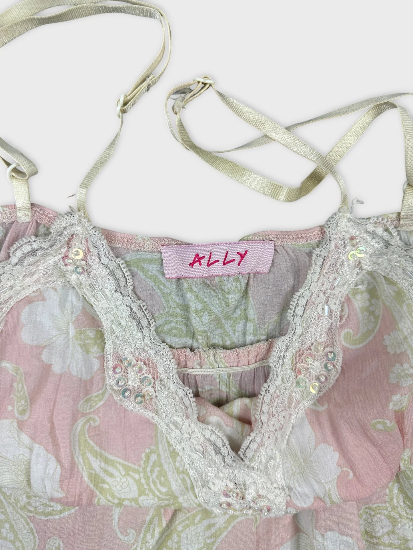 Detail view of a vintage pink floral top with lace trim.