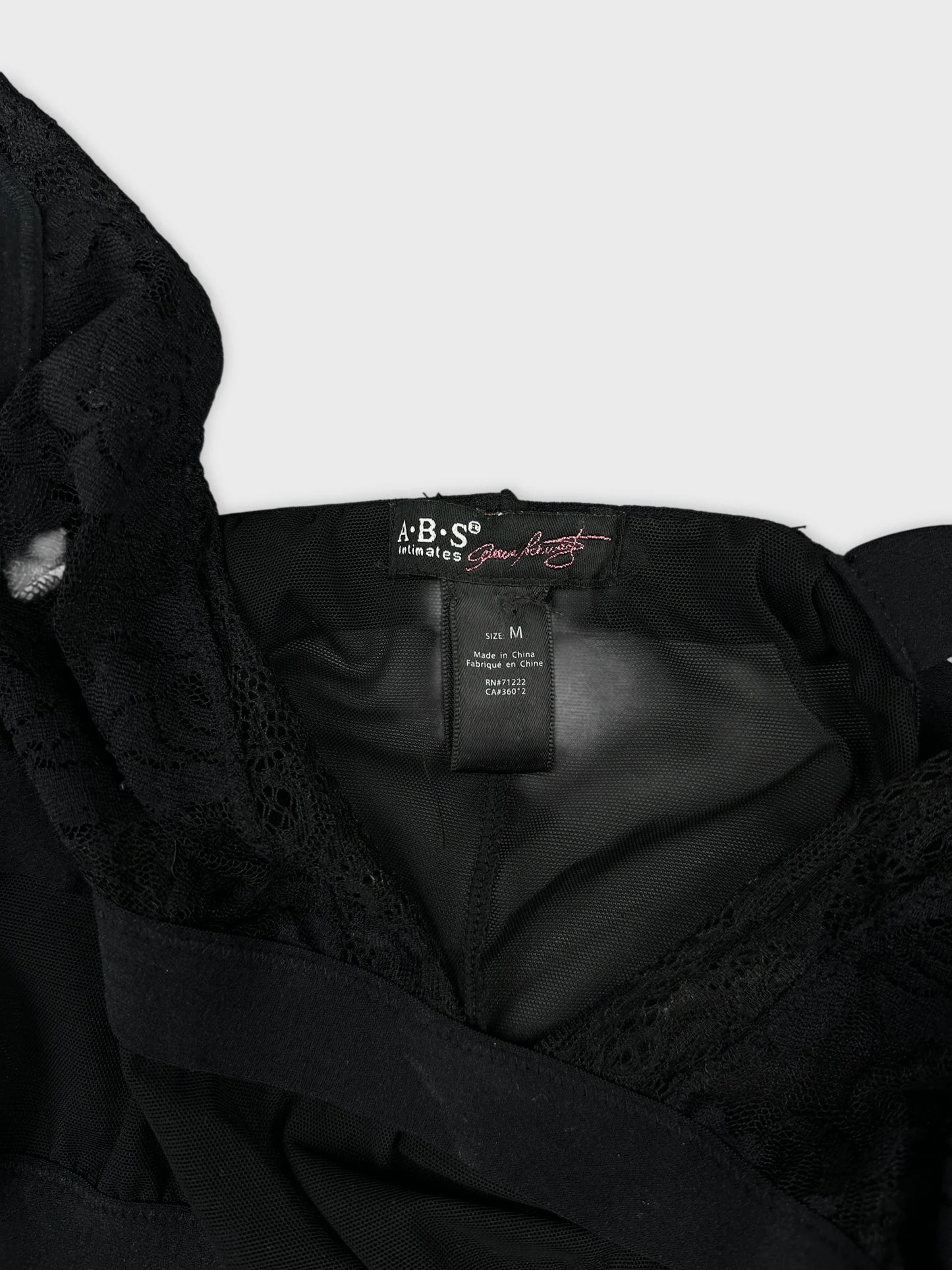 Detail view of a black women's upper body top featuring lace trim.