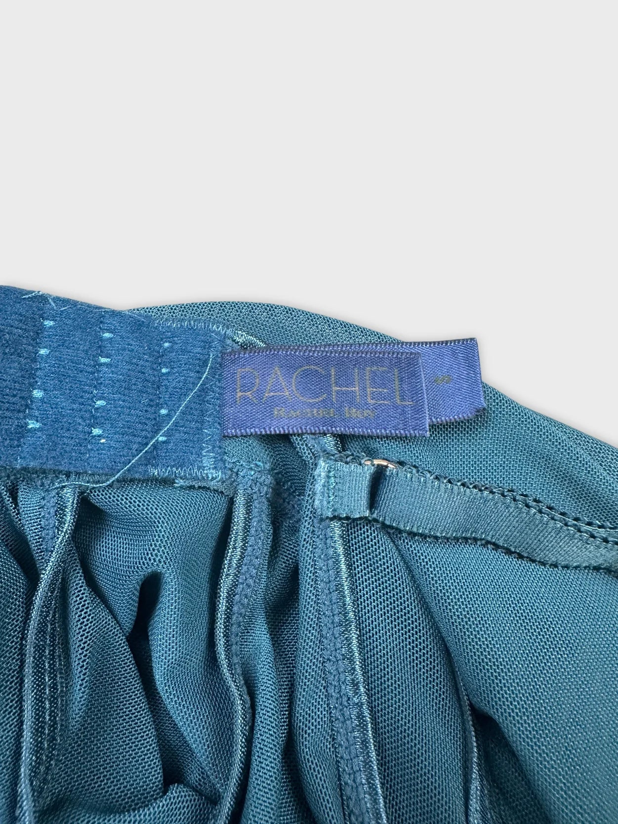 Detail view of a teal upper body top featuring gathered fabric.