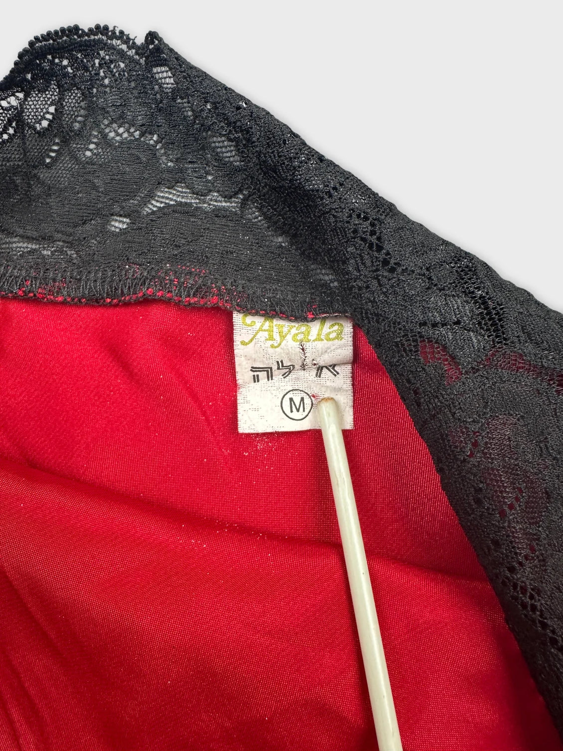 Detail view of a vintage red top with black lace trim