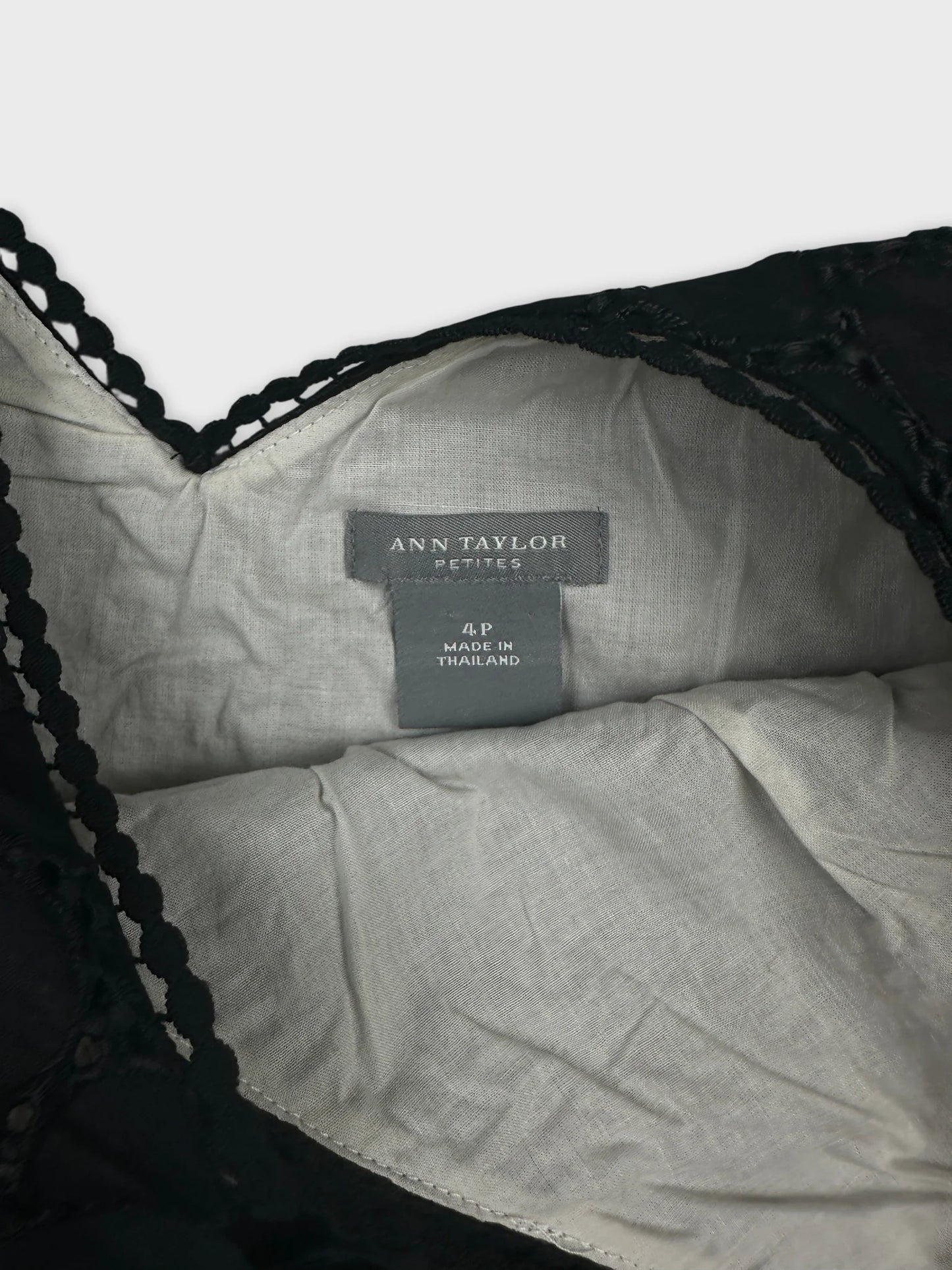 Detail view of a black vintage top with lace trim and tag.
