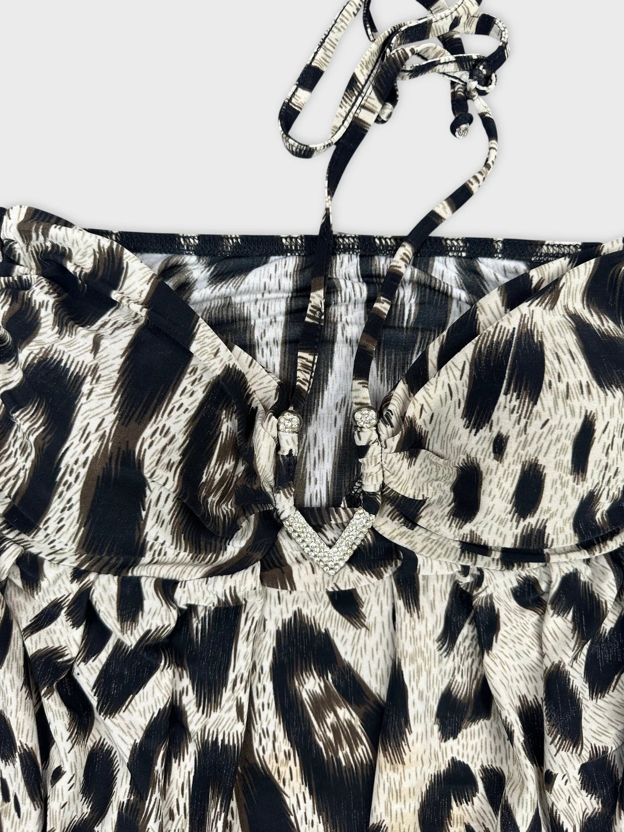 Detail view of a leopard print top in black and cream with a jewel accent.