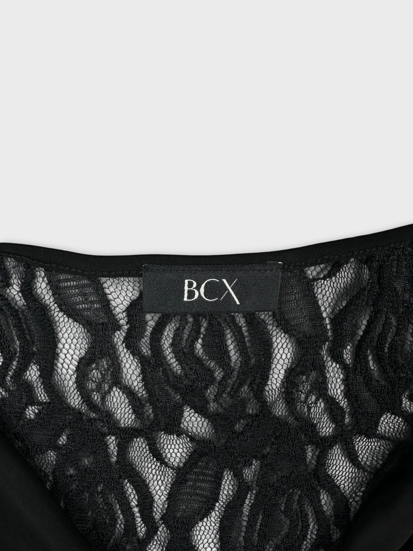 Detail view of a black women's top featuring lace details.