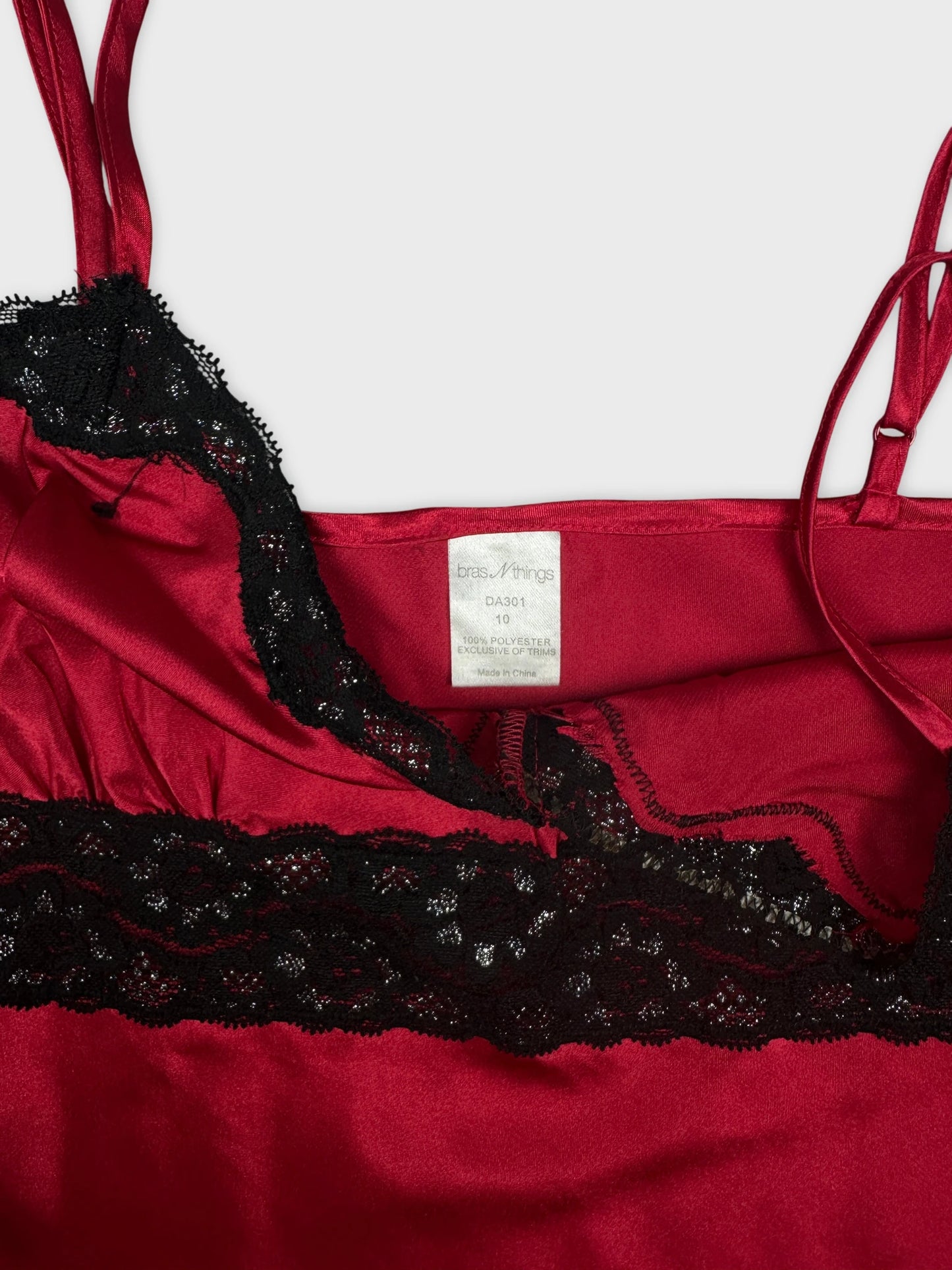 Detail view of a red satin top with black lace trim.
