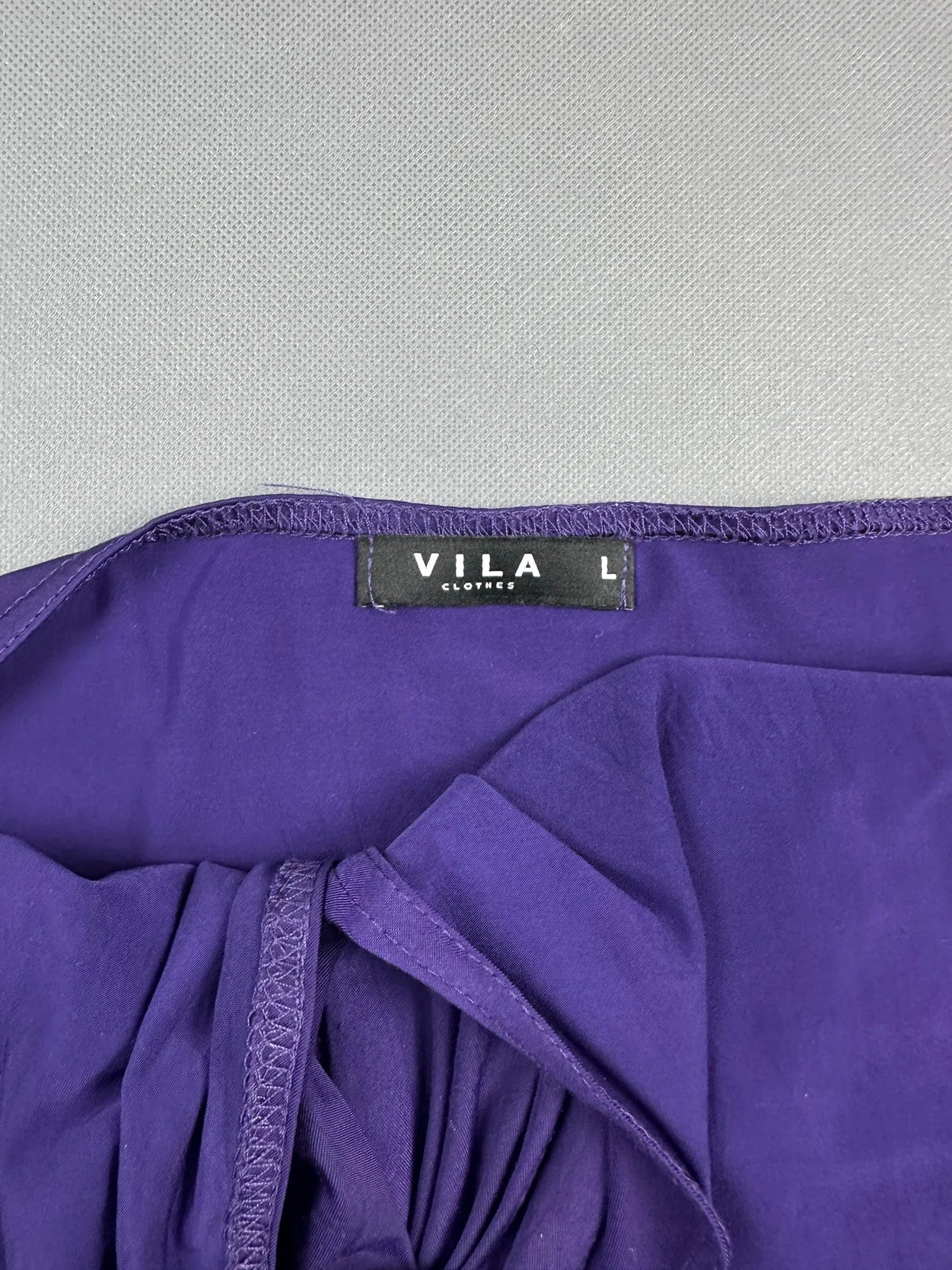 Detail view of a purple women's top with gathered fabric.