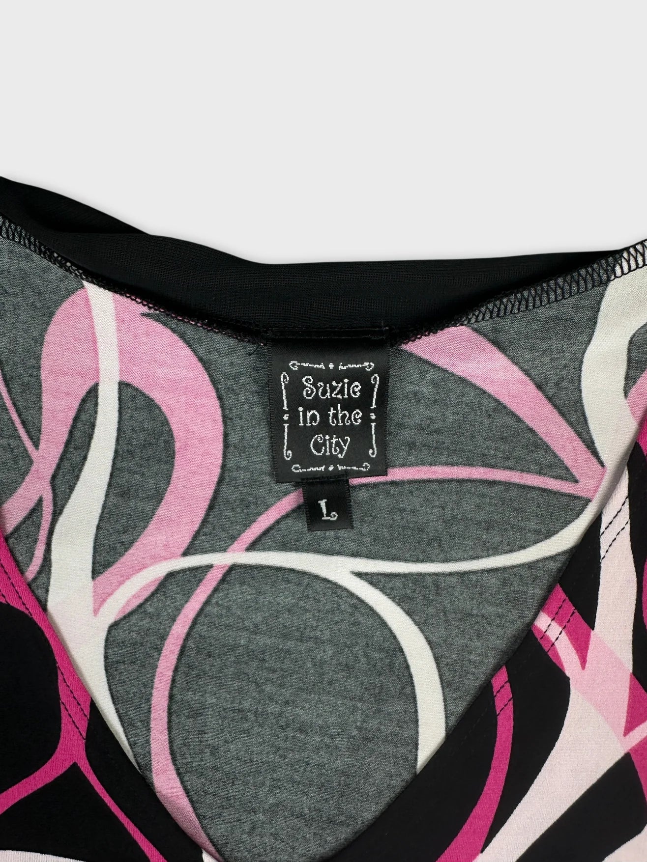 Detail view of a gray women’s top with pink and white swirl pattern.