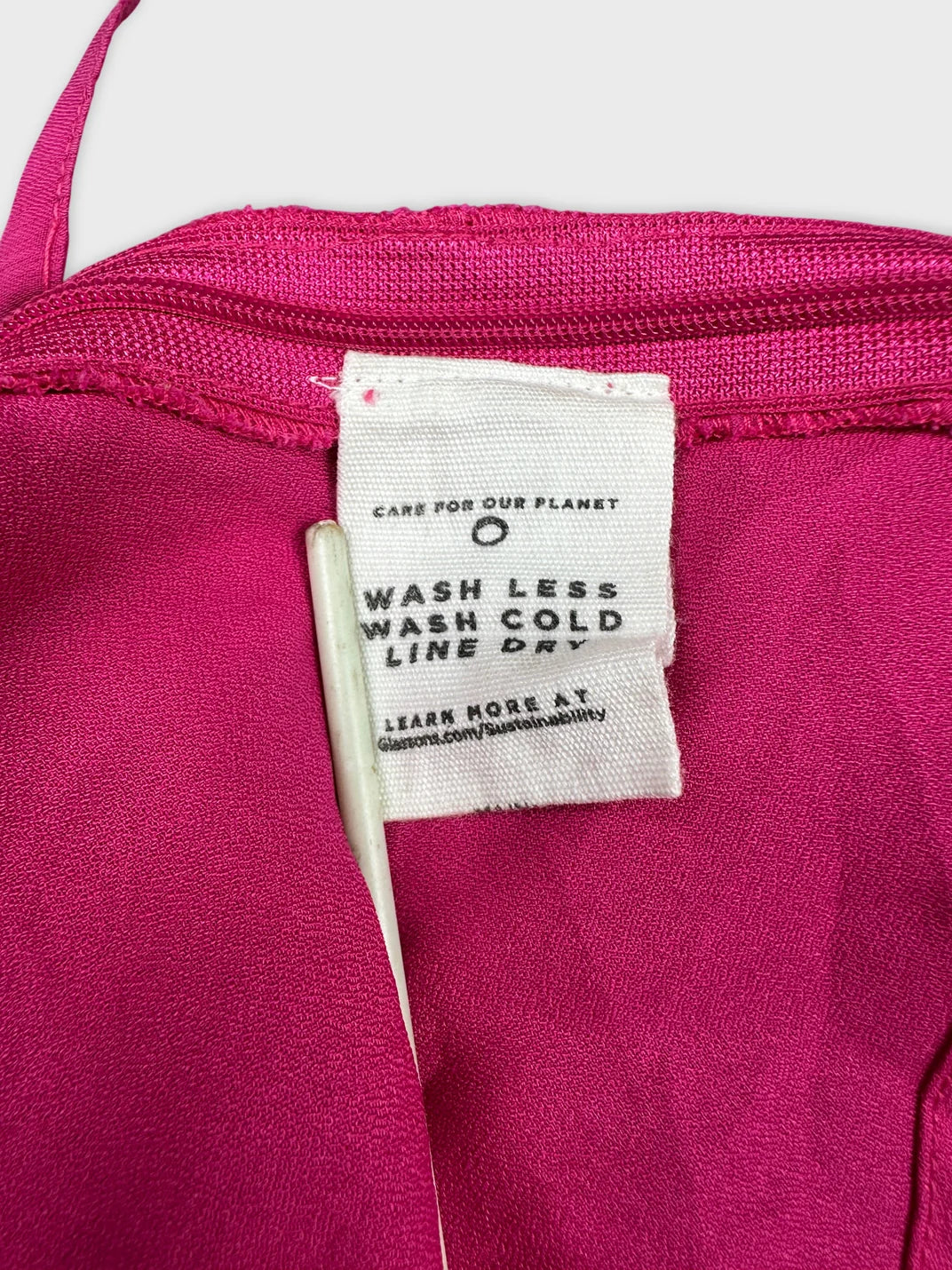 Detail view of a pink women's top showing zipper and care tag.