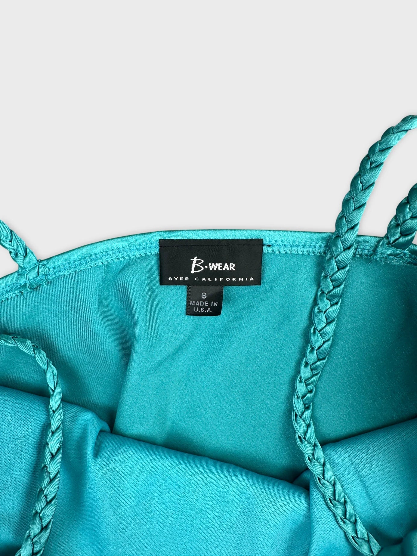 Detail view of a women's turquoise upper body top with braided straps.