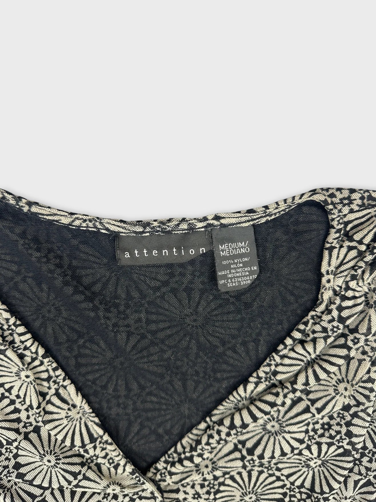 Detail view of a vintage women’s top featuring a floral pattern in black and cream.