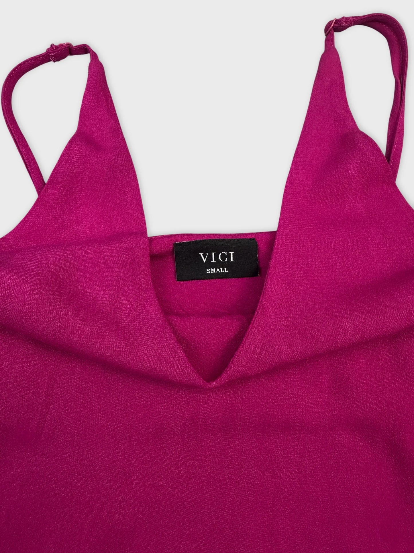 Detail view of a women's top in vibrant magenta with a V-neck design.