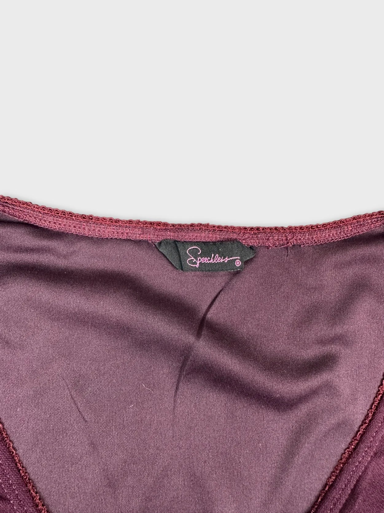 Detail view of a maroon women’s upper body top with a smooth neckline.