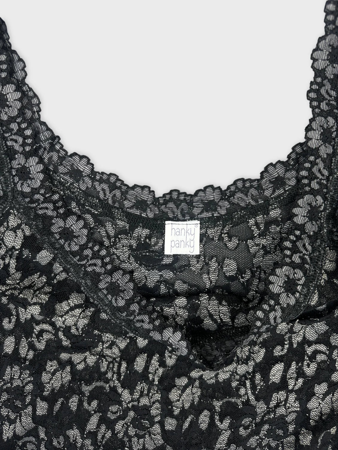 Detail view of a black lace top with floral pattern and scalloped edges.