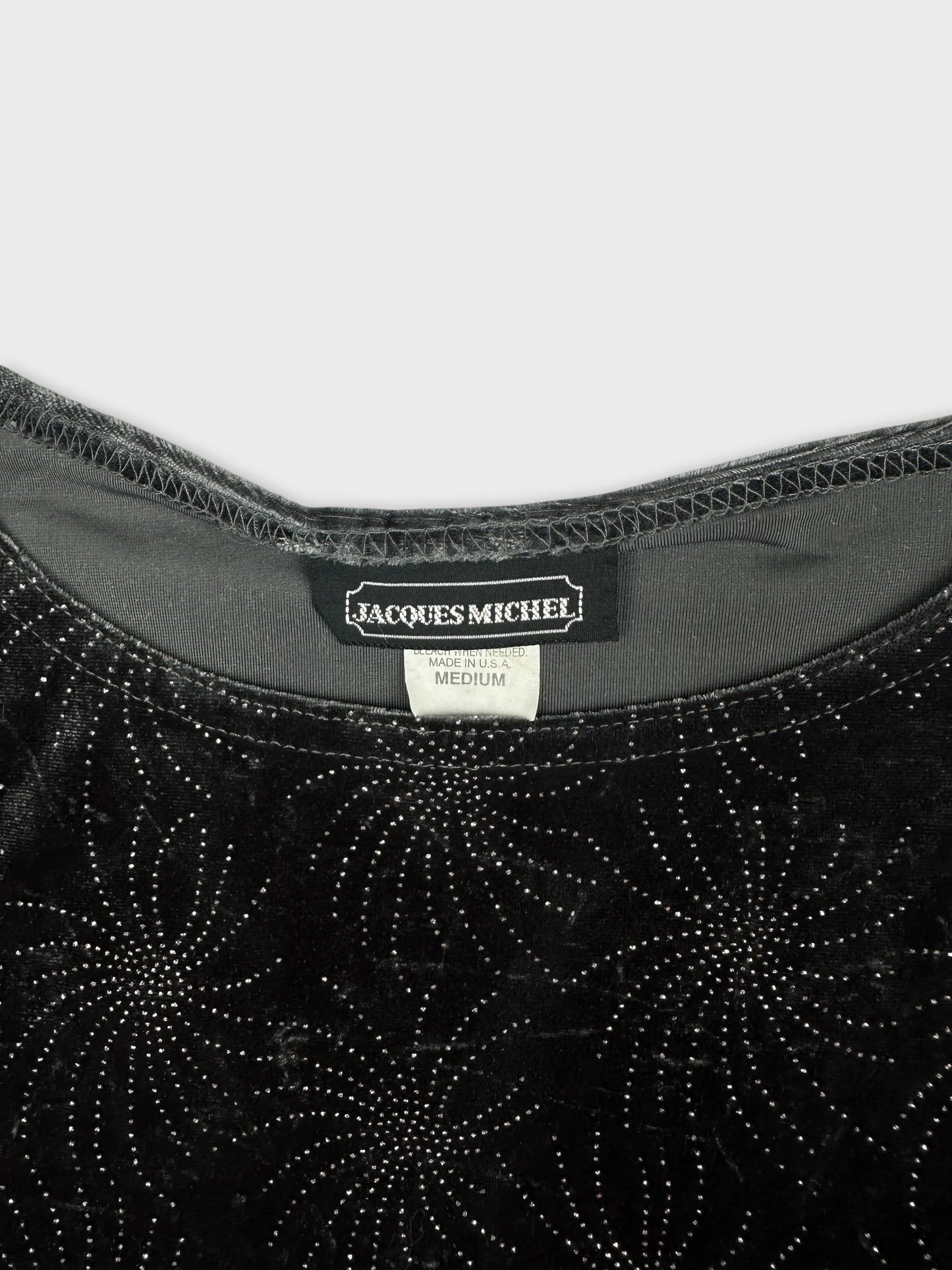 Detail view of black velvet upper body top with metallic swirl pattern.