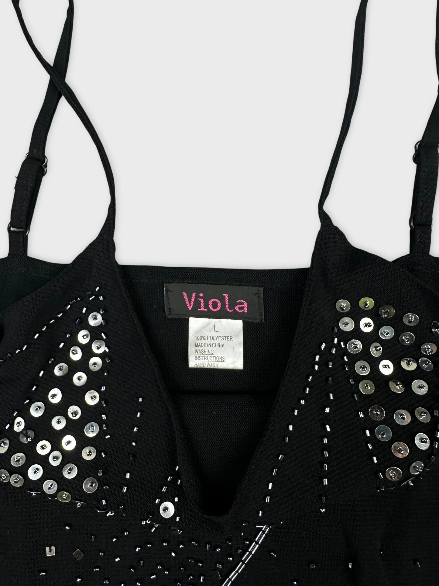 Detail view of a black top featuring sequin embellishments and spaghetti straps.