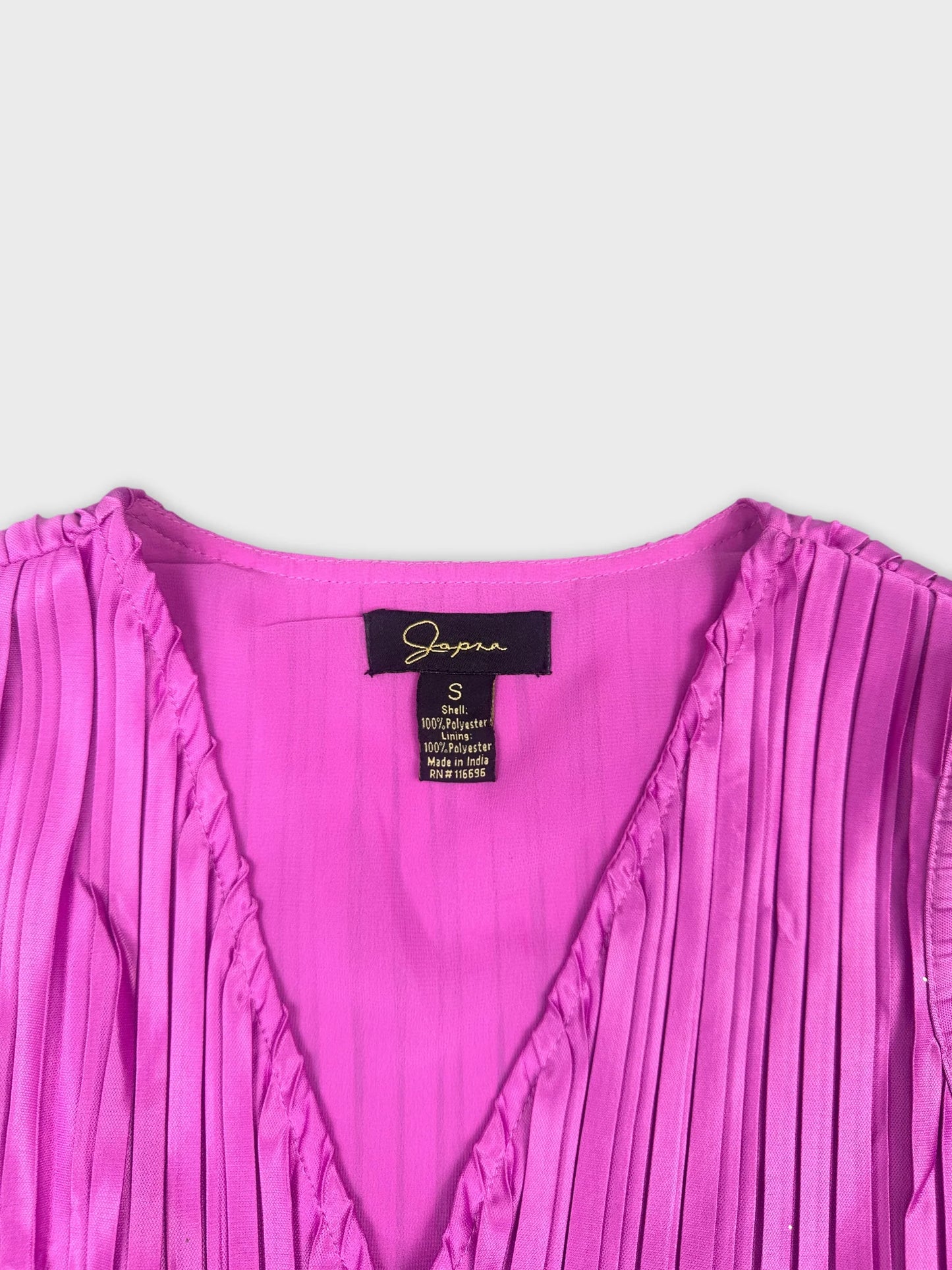 Detail view of a pink pleated women's top with a V-neckline.