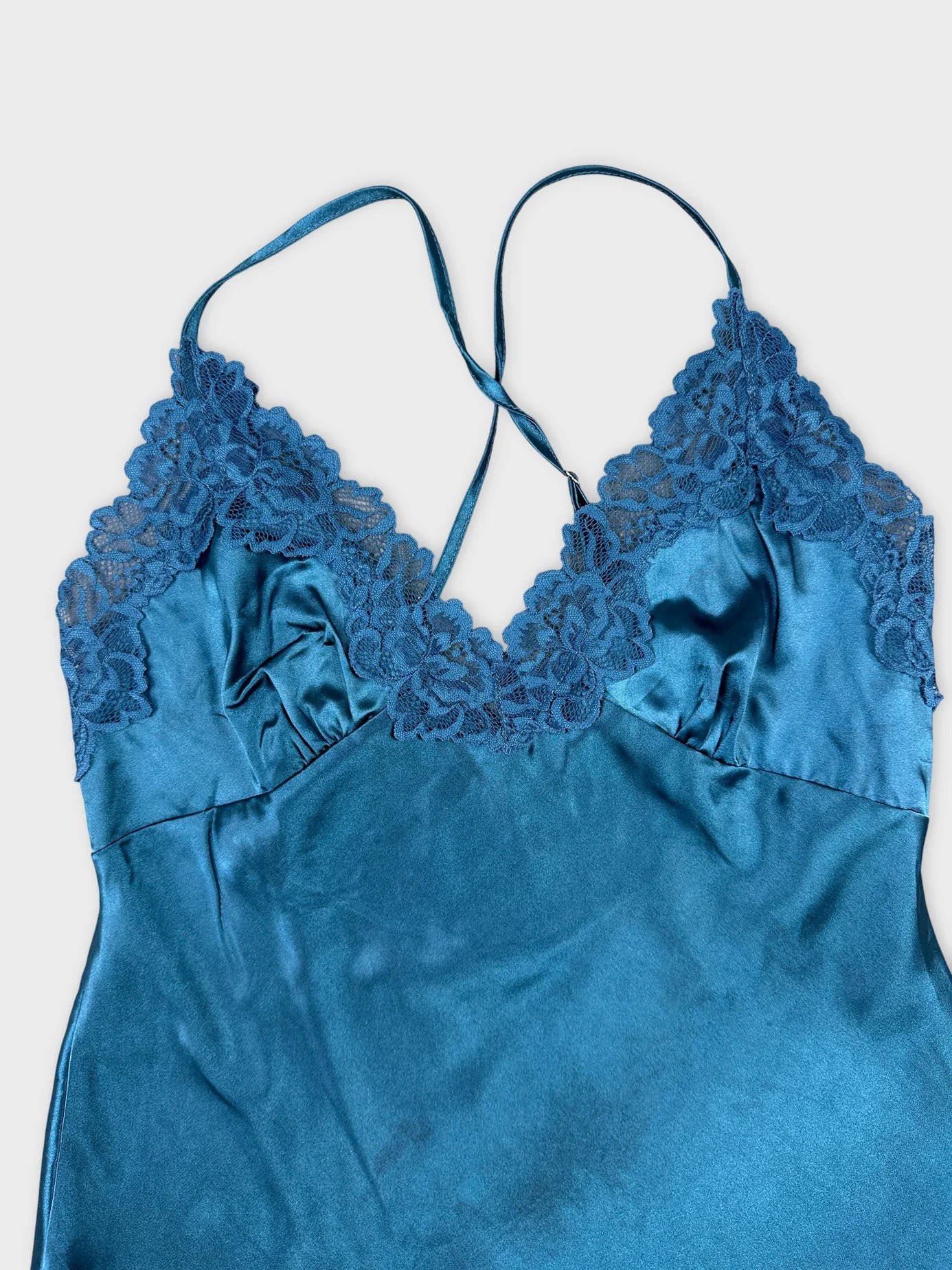 Detail view of a blue satin camisole with lace trim.