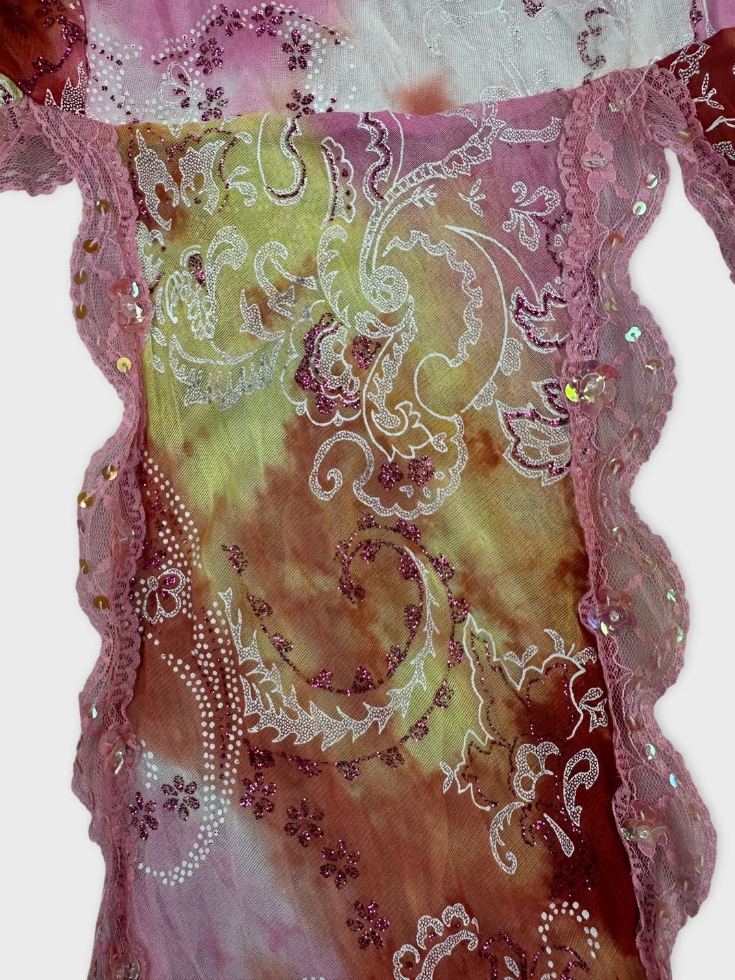 Detail view of a women's top in pink featuring floral lace trim and bead embellishments.