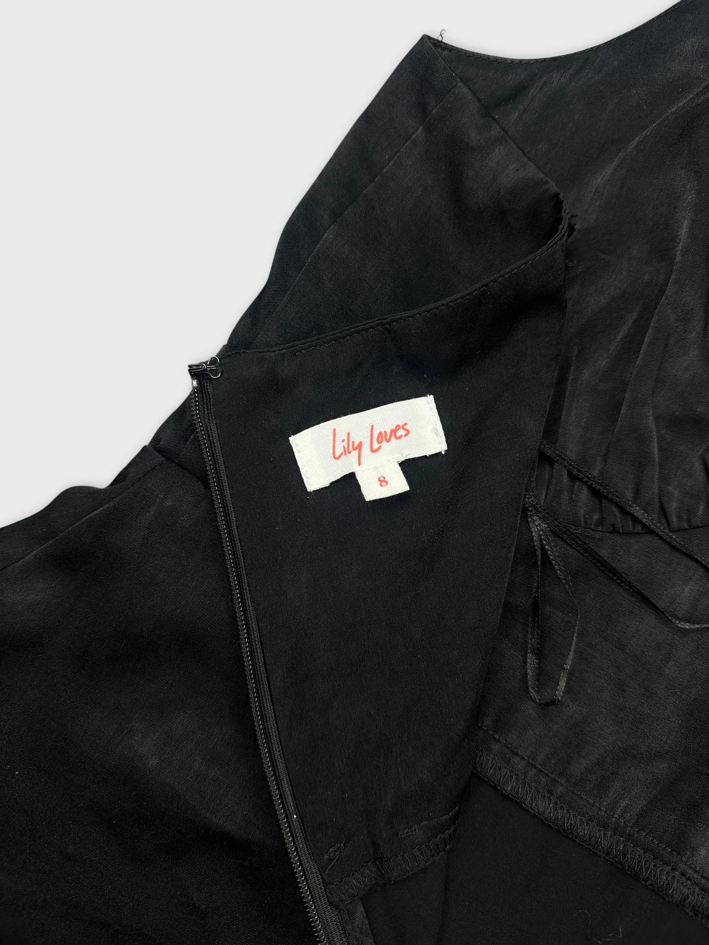 Black top detail view showing zipper and brand tag inside.