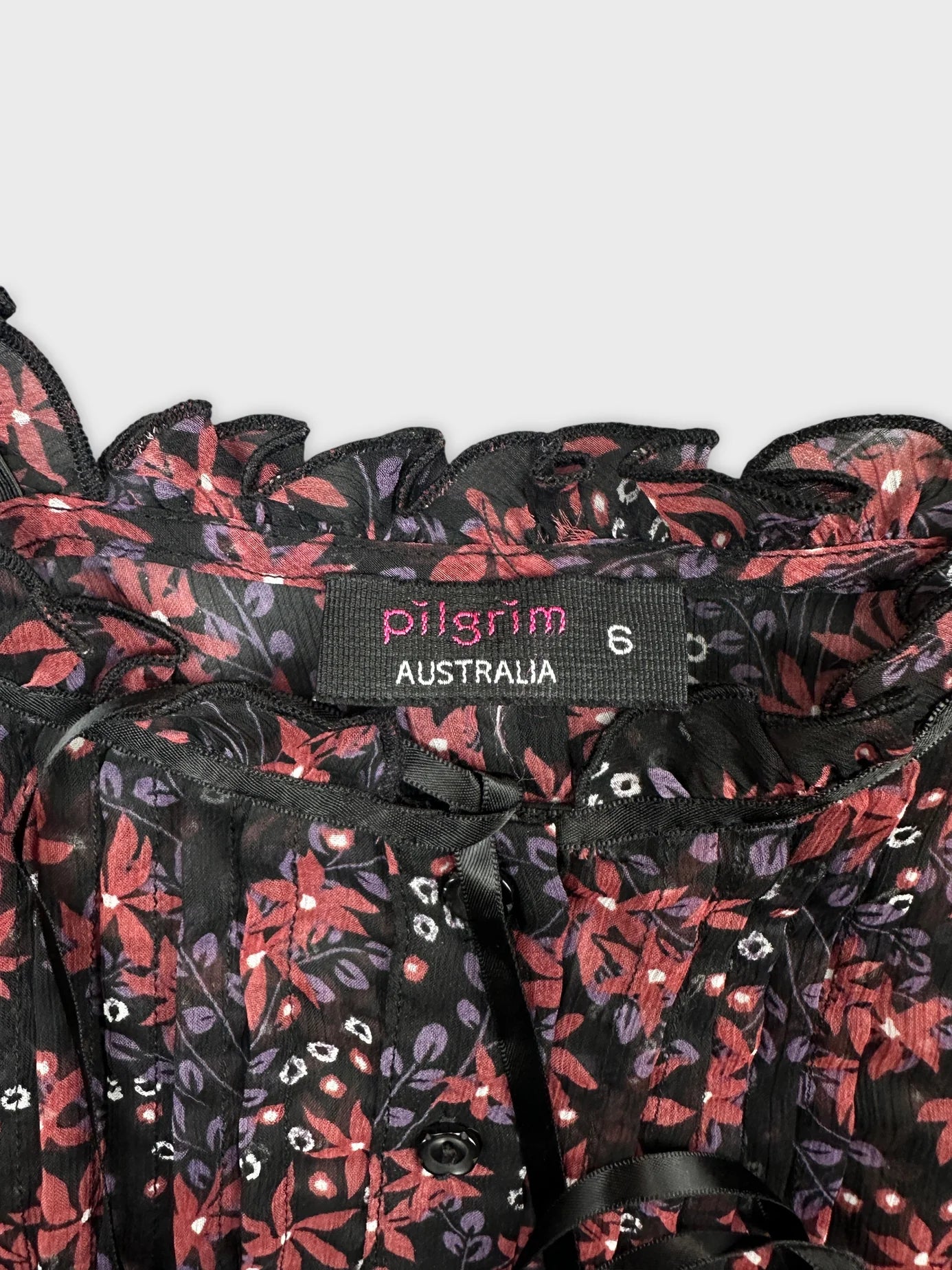 Detail view of a black vintage top with floral print and ruffled neckline