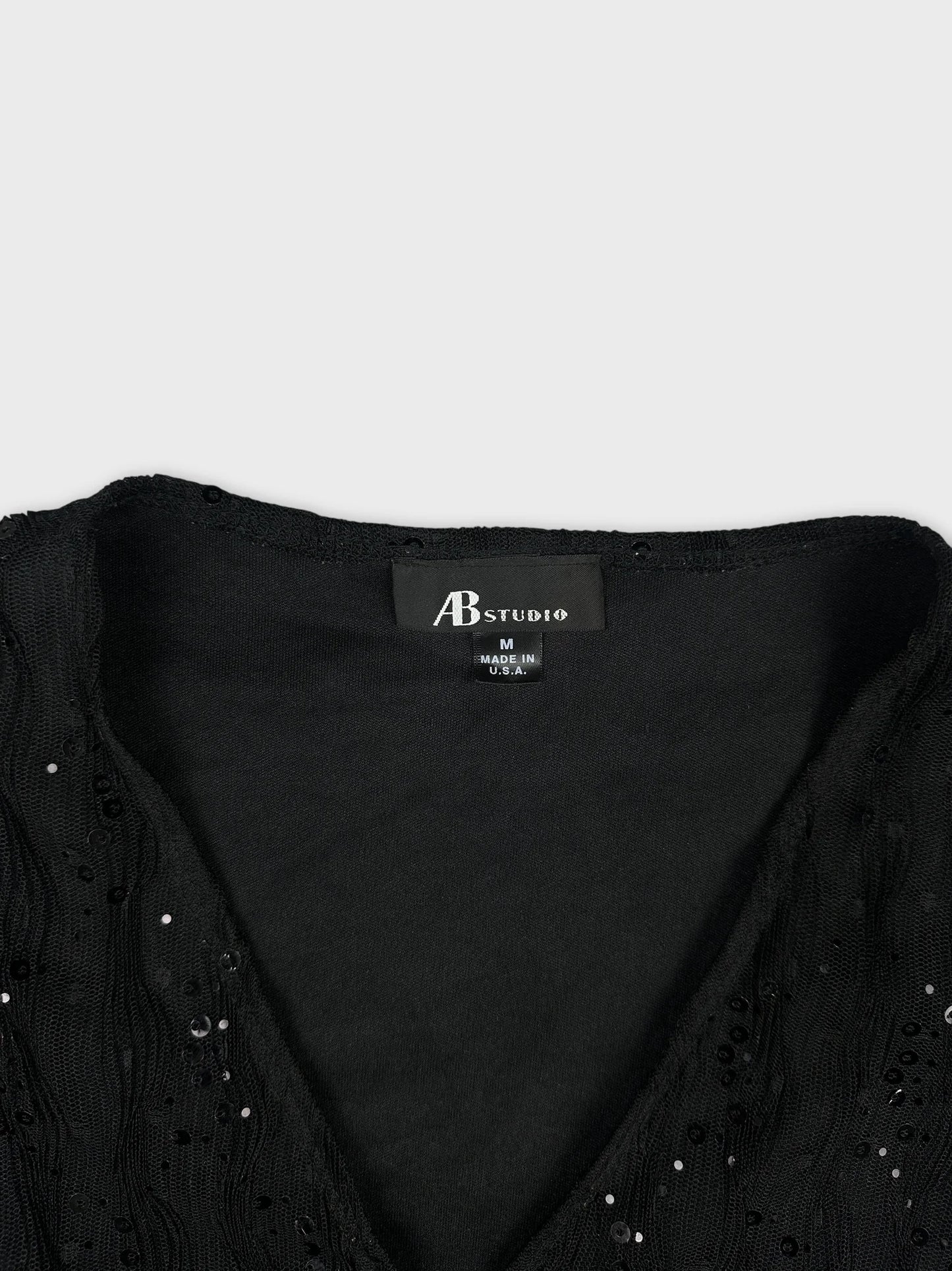 Detail view of a black vintage women’s top with textured sequined trim.