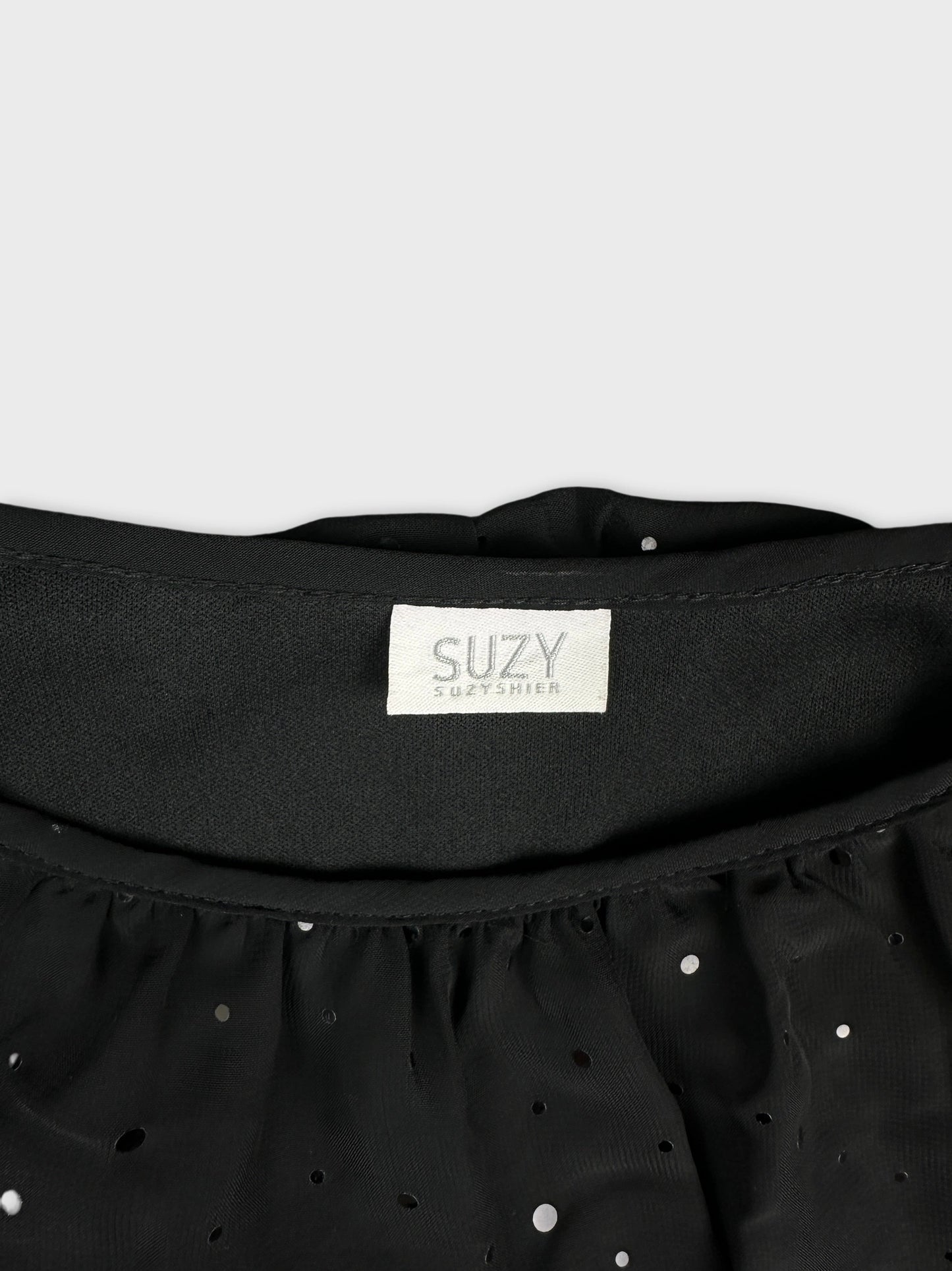Detail view of a black upper body top with polka dot pattern.