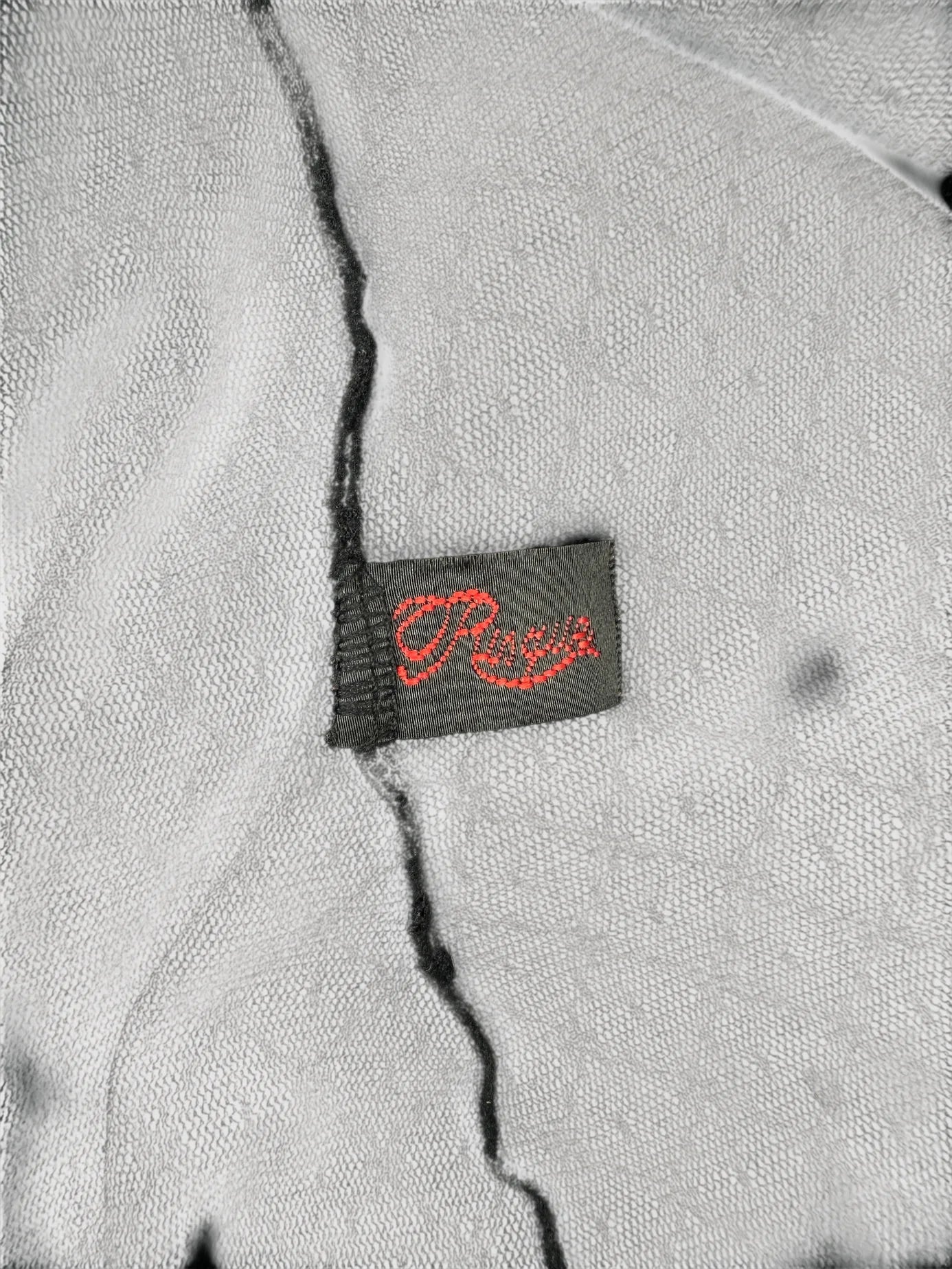 Detail view of a gray vintage top featuring a red printed label.