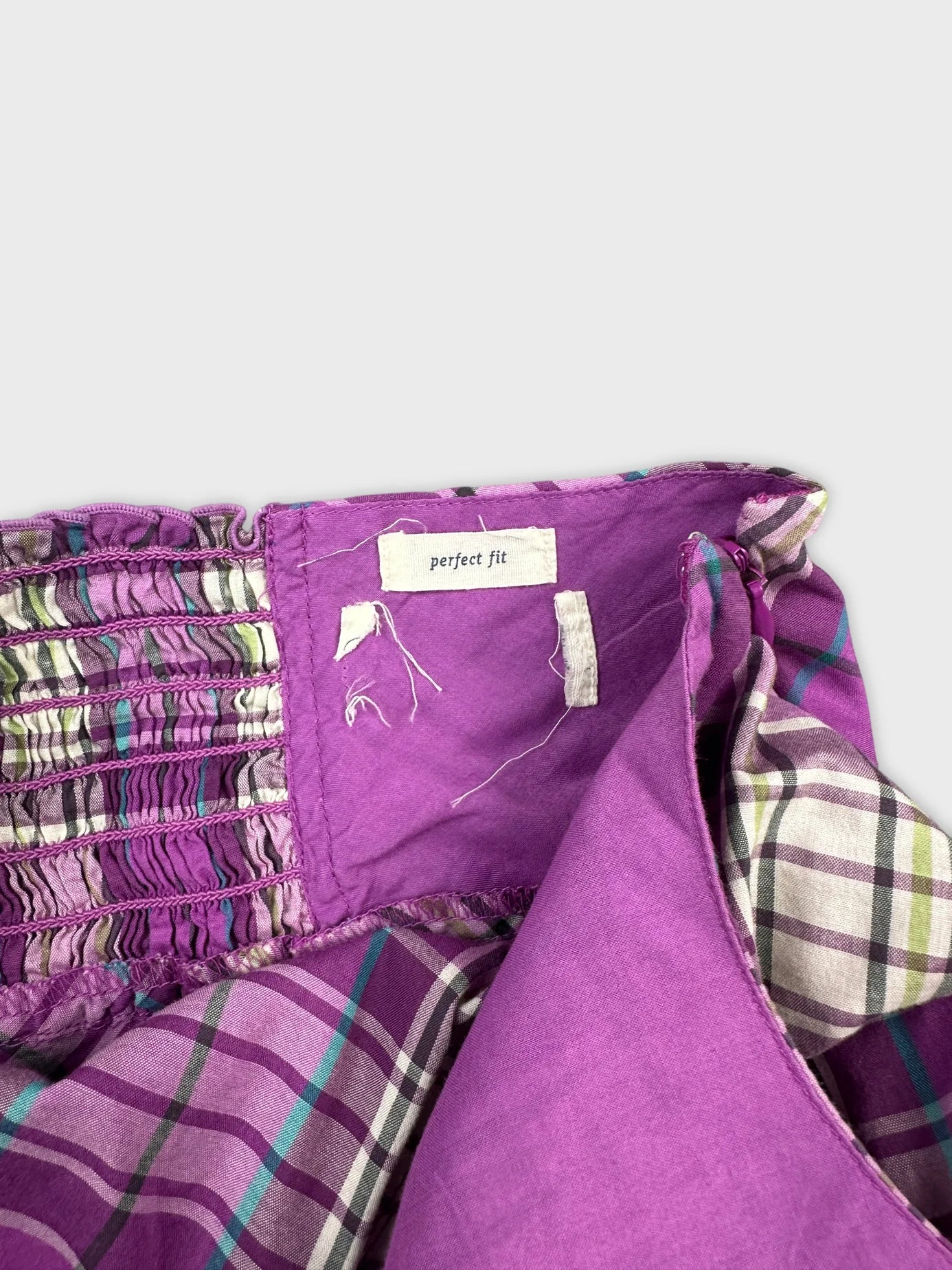 Detail view of a purple vintage top featuring ruched texture and plaid lining.