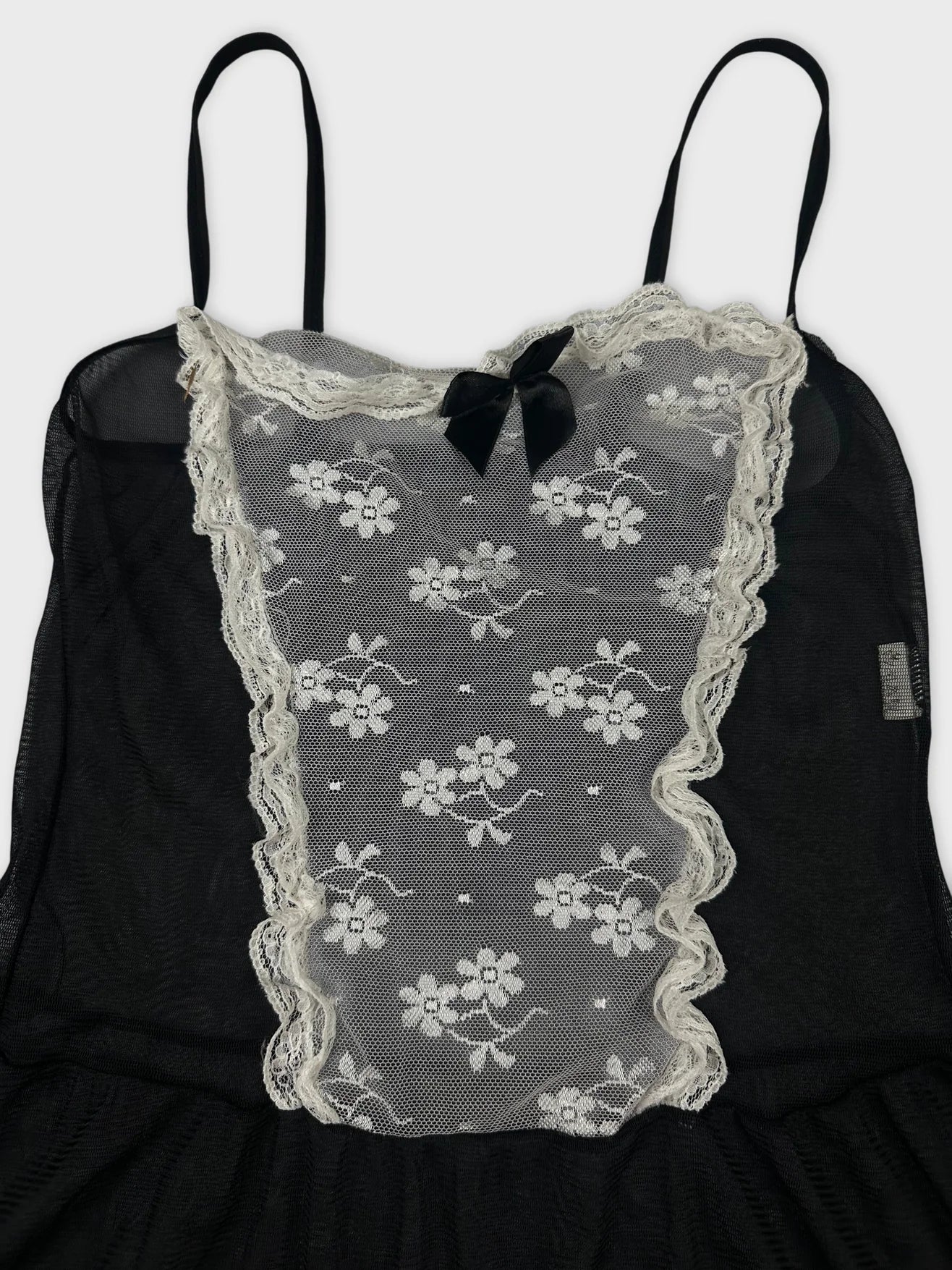 Detail view of a black vintage top with lace floral pattern and bow.