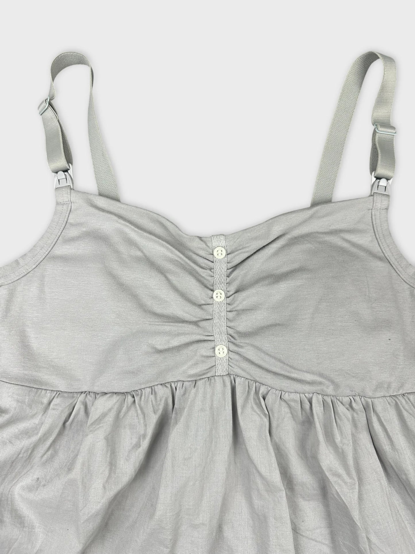 Detail view of a gray upper body top with button details and gathered fabric.